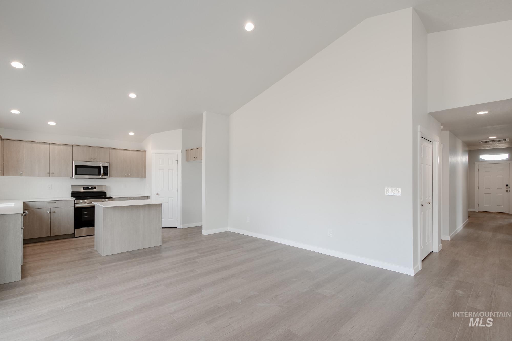 Kitchen with recessed lighting, a kitchen island, light countertops, appliances with stainless steel finishes, and light wood-style floors