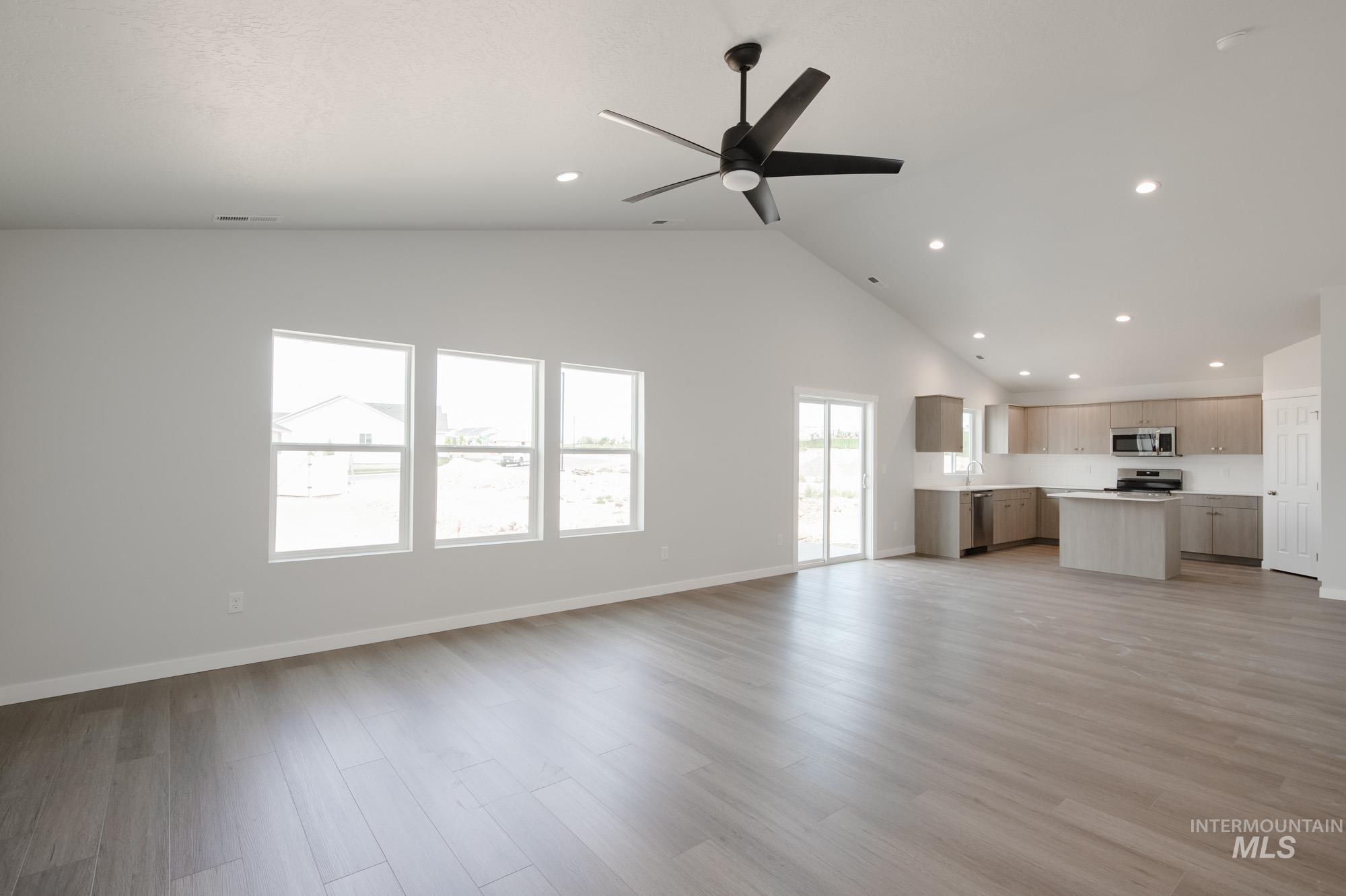 Unfurnished living room featuring light wood finished floors, recessed lighting, high vaulted ceiling, and ceiling fan