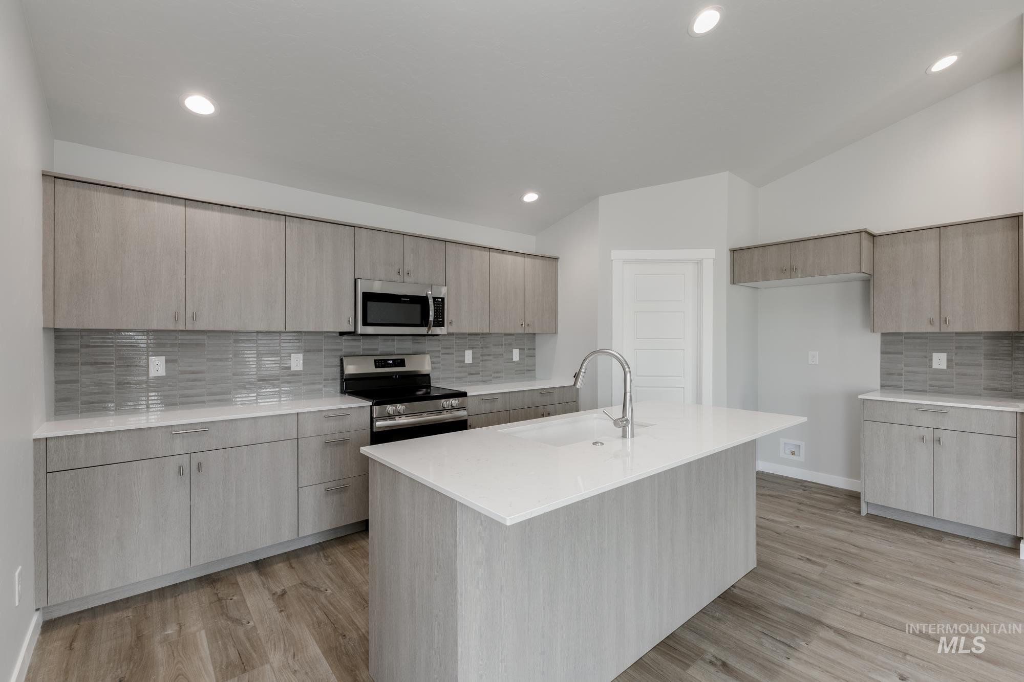 Kitchen featuring backsplash, light stone counters, stainless steel appliances, modern cabinets, and light wood-type flooring