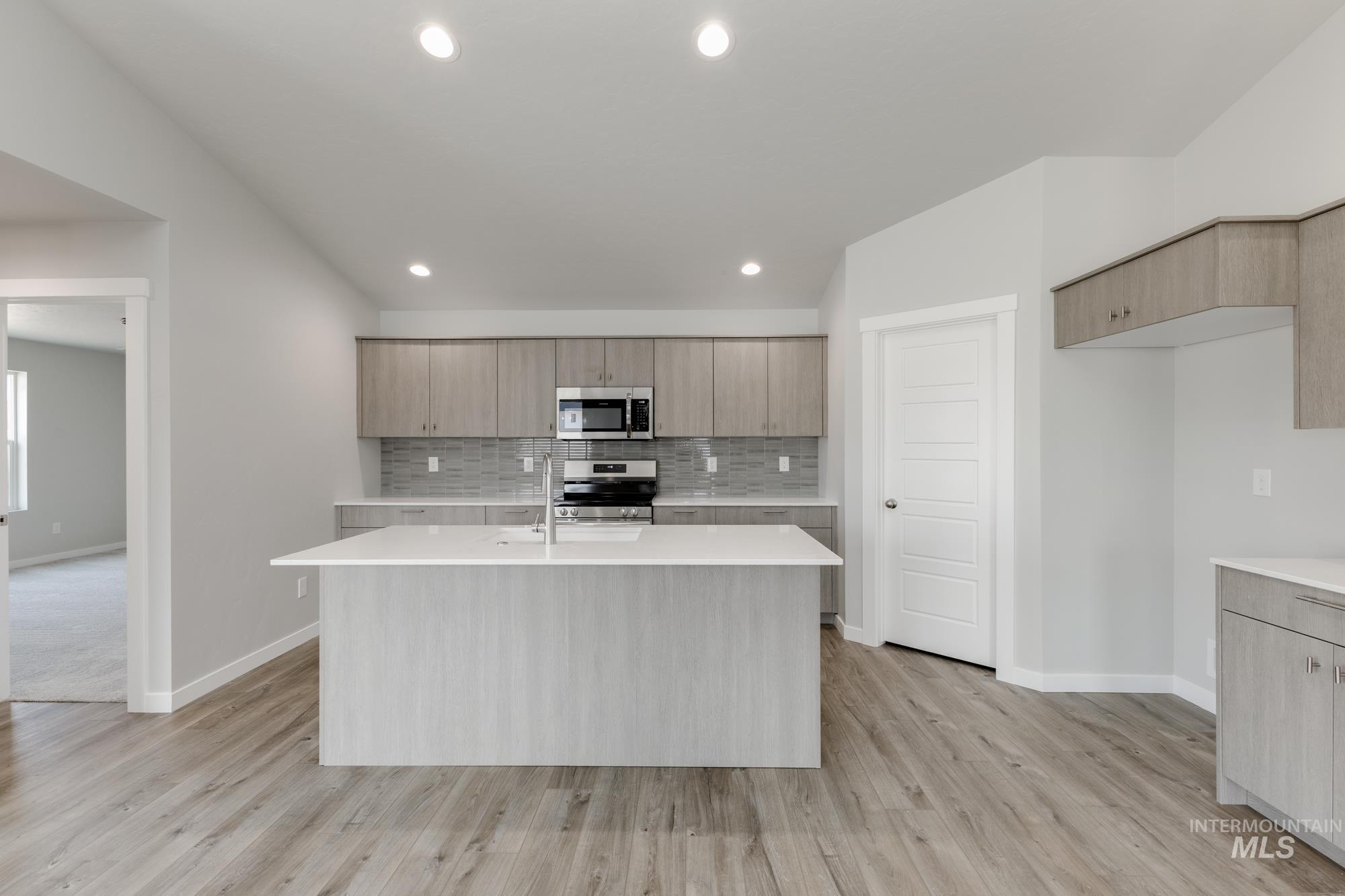 Kitchen featuring tasteful backsplash, an island with sink, stainless steel appliances, modern cabinets, and recessed lighting