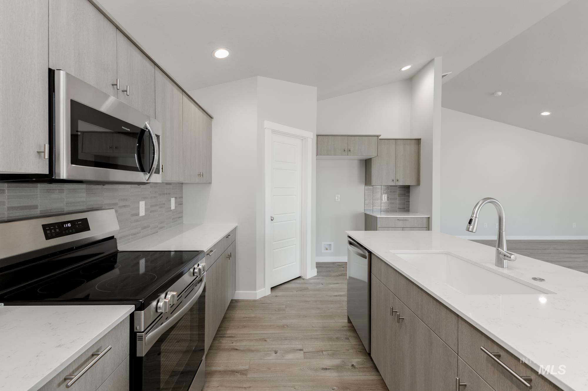 Kitchen featuring stainless steel appliances, backsplash, light wood-type flooring, light stone counters, and recessed lighting