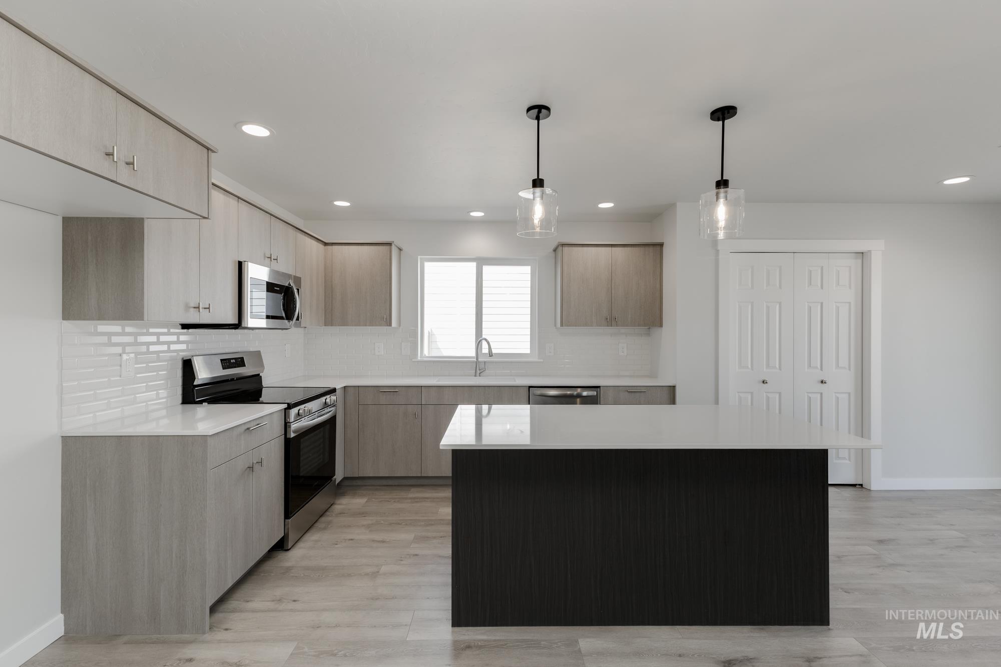 Kitchen with appliances with stainless steel finishes, modern cabinets, light brown cabinets, and recessed lighting