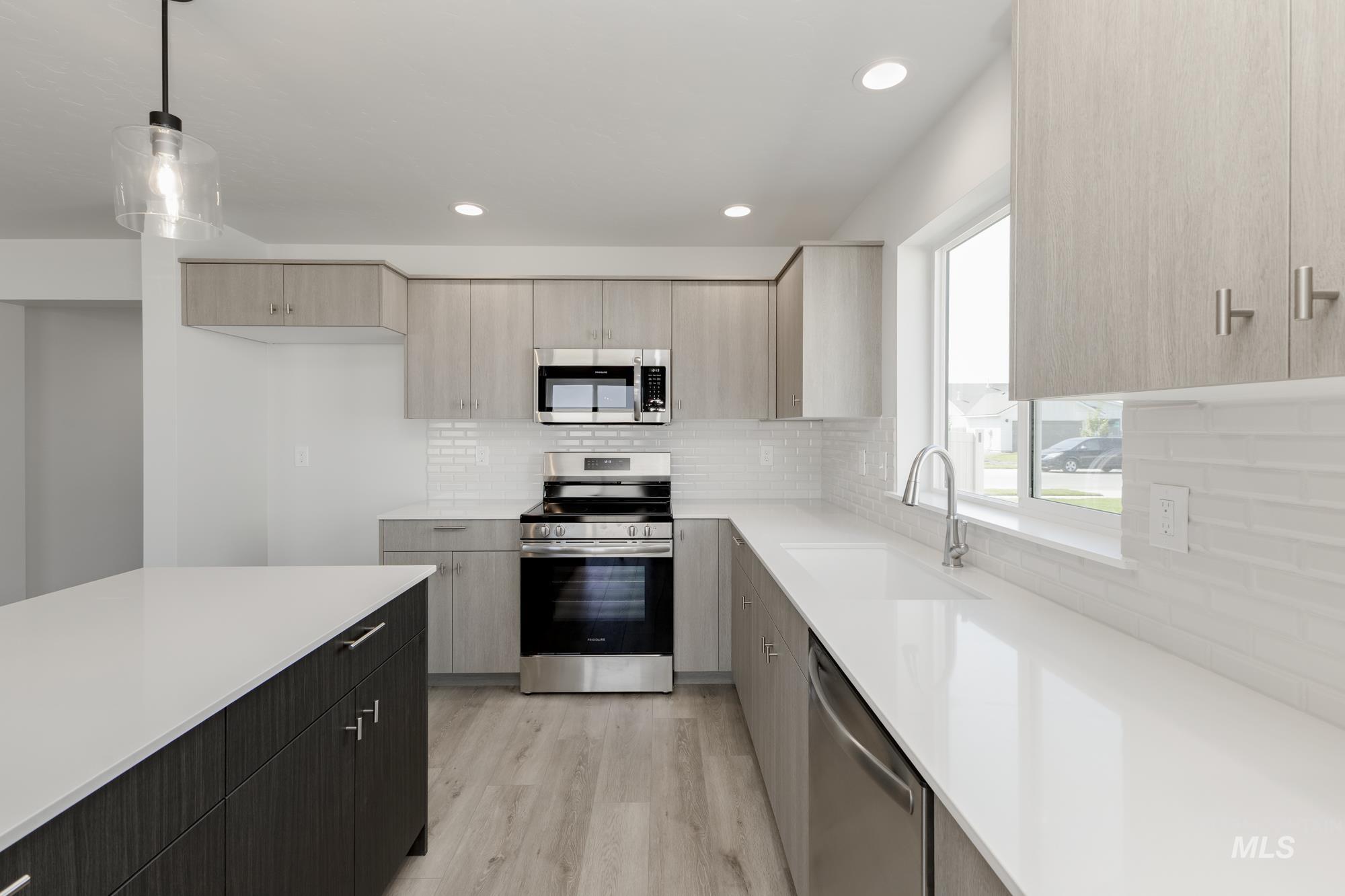 Kitchen with stainless steel appliances, decorative backsplash, light wood finished floors, decorative light fixtures, and recessed lighting