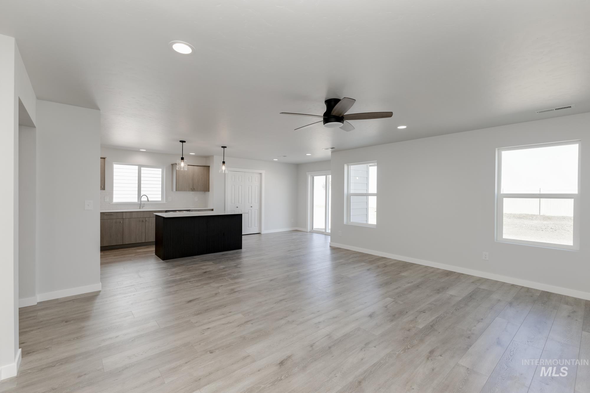 Unfurnished living room featuring light wood-style floors, a ceiling fan, and recessed lighting