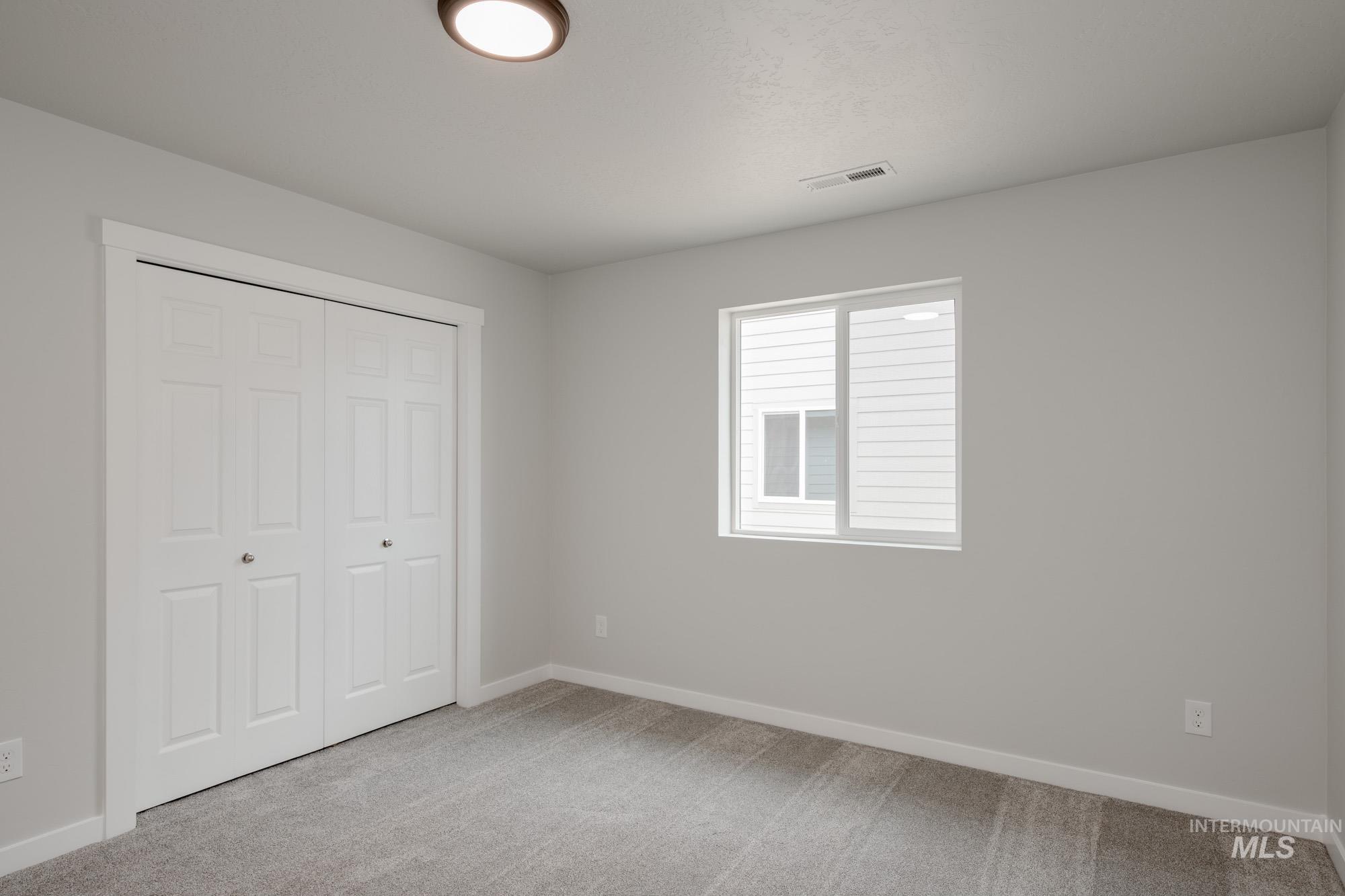 Unfurnished bedroom with light carpet and a closet