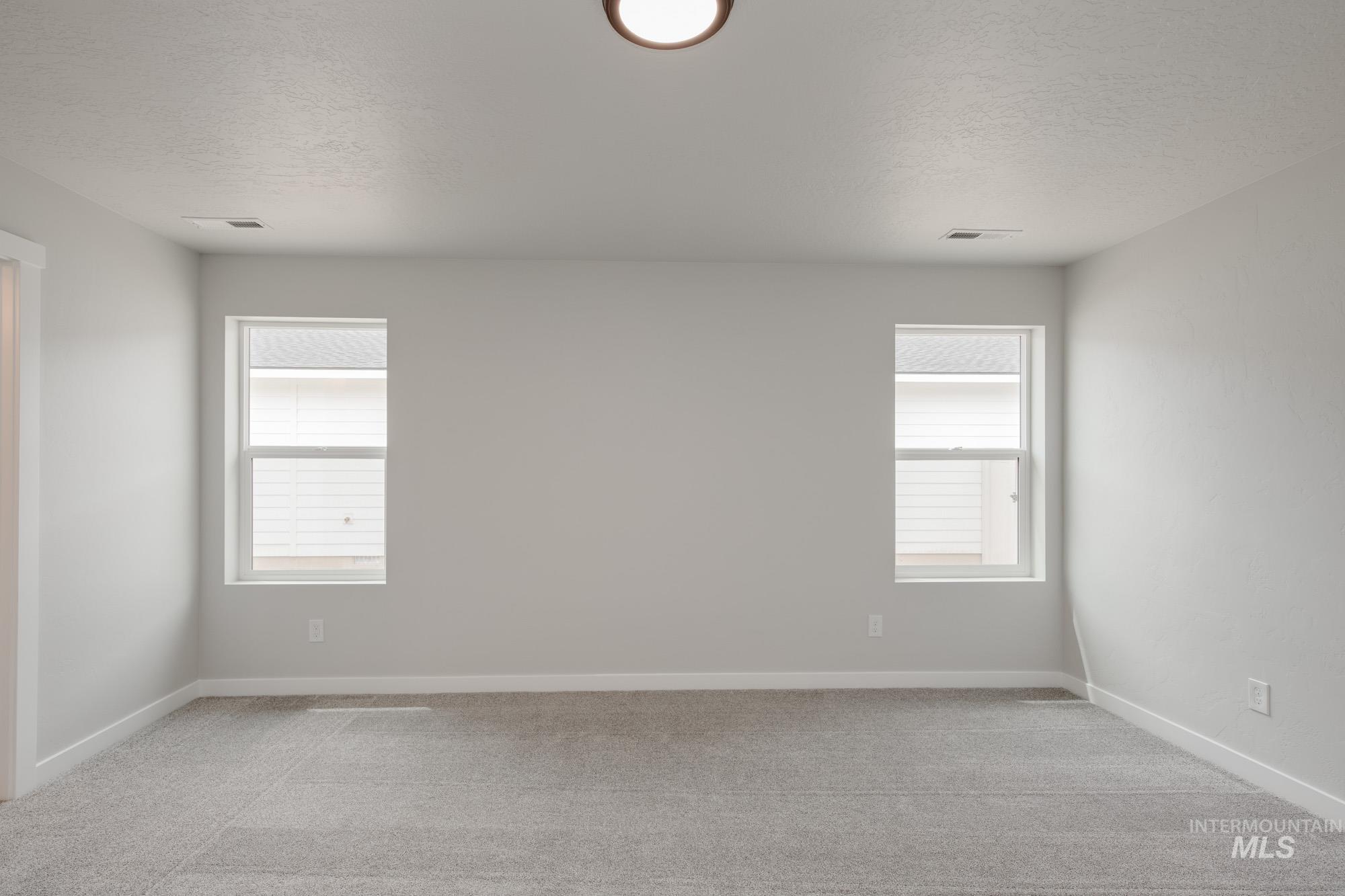 Empty room featuring a textured ceiling and light carpet