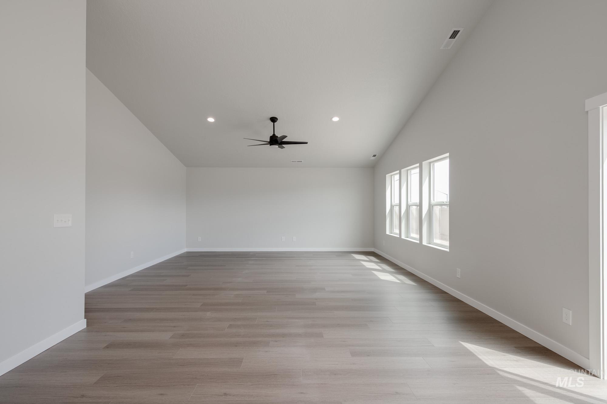 Unfurnished room with lofted ceiling, light wood-type flooring, recessed lighting, and a ceiling fan