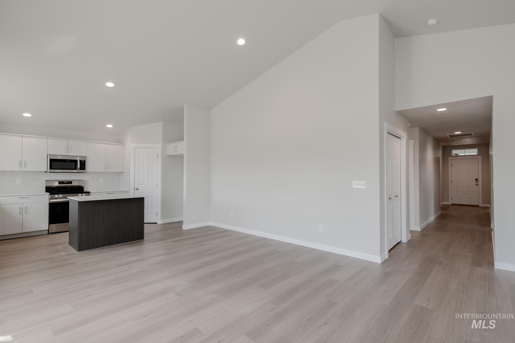 Kitchen featuring recessed lighting, a kitchen island, white cabinets, appliances with stainless steel finishes, and light wood-type flooring