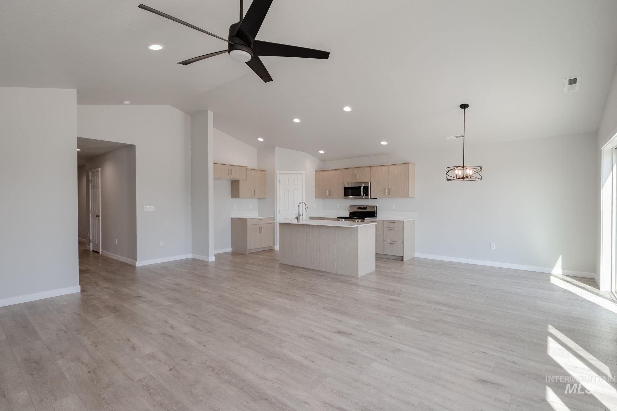 Unfurnished living room featuring light wood-style flooring, vaulted ceiling, a ceiling fan, and recessed lighting