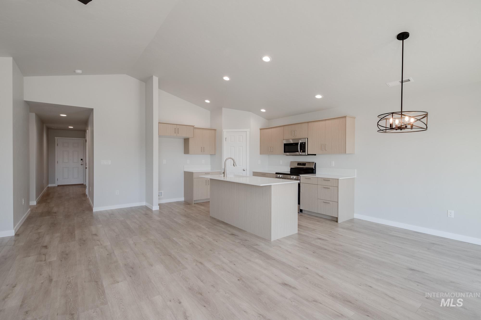 Kitchen featuring a center island with sink, light wood-style floors, lofted ceiling, open floor plan, and recessed lighting