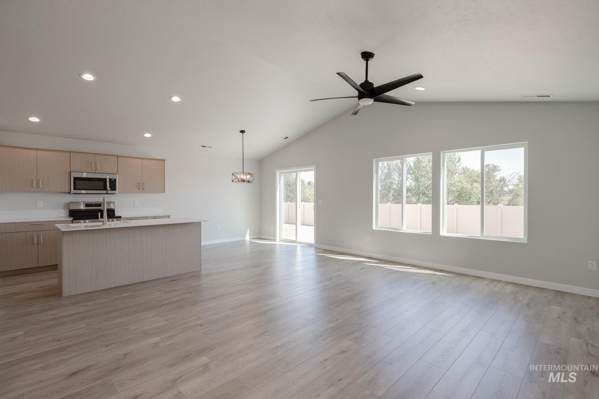 Unfurnished living room with vaulted ceiling, light wood-style floors, ceiling fan, recessed lighting, and a chandelier