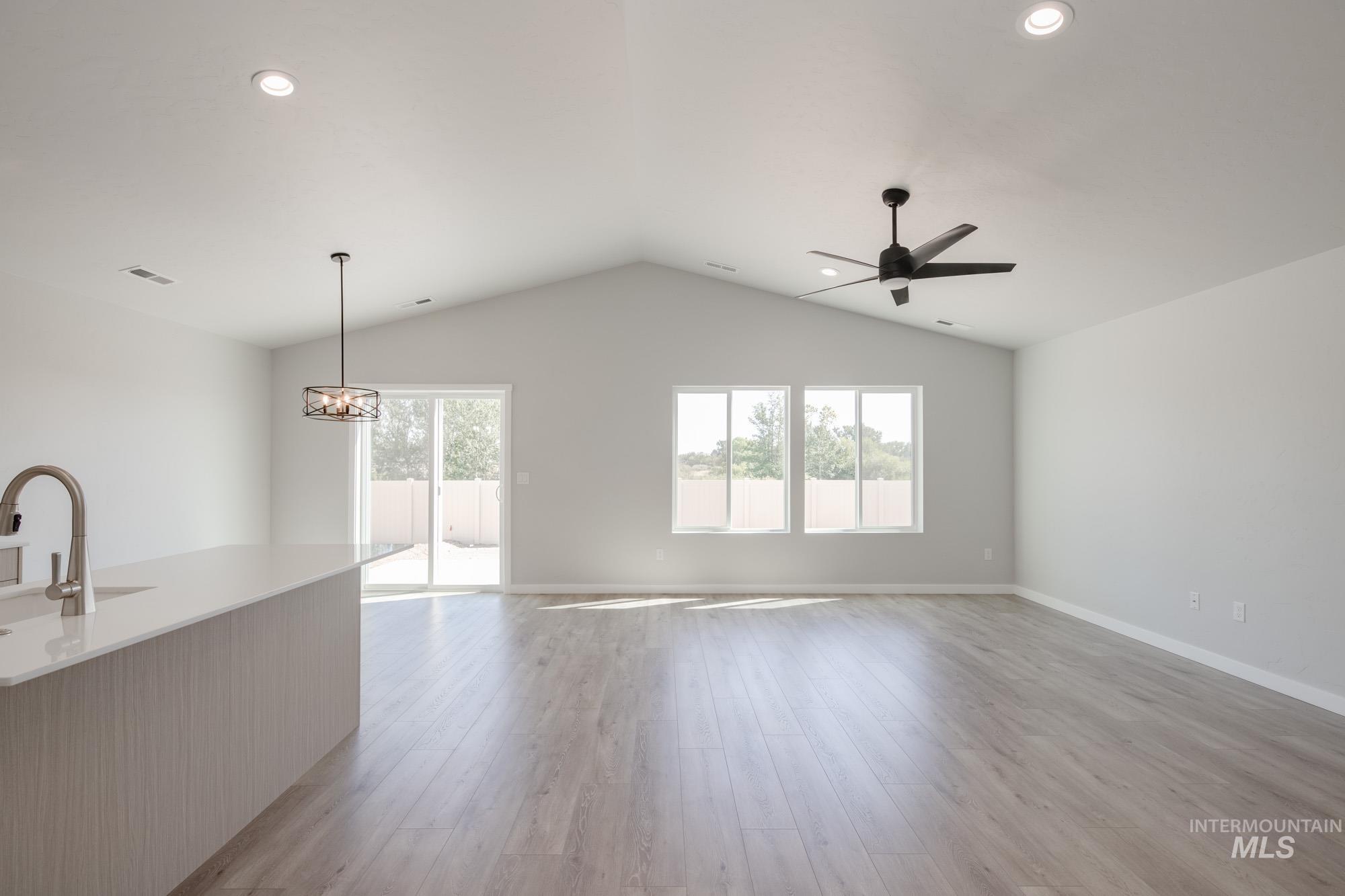 Unfurnished living room with light wood-style flooring, lofted ceiling, recessed lighting, a chandelier, and ceiling fan
