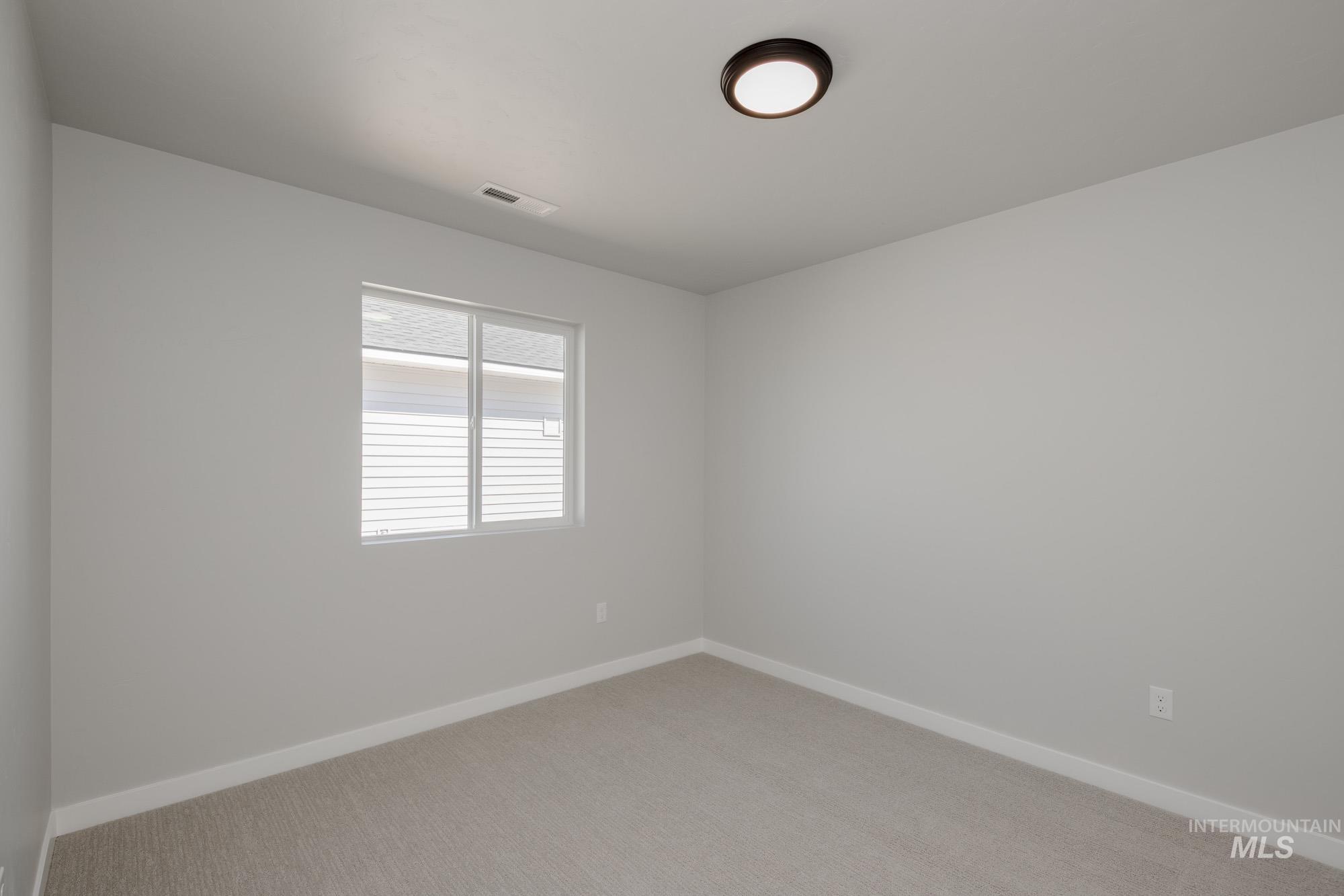 Empty room featuring baseboards and light colored carpet