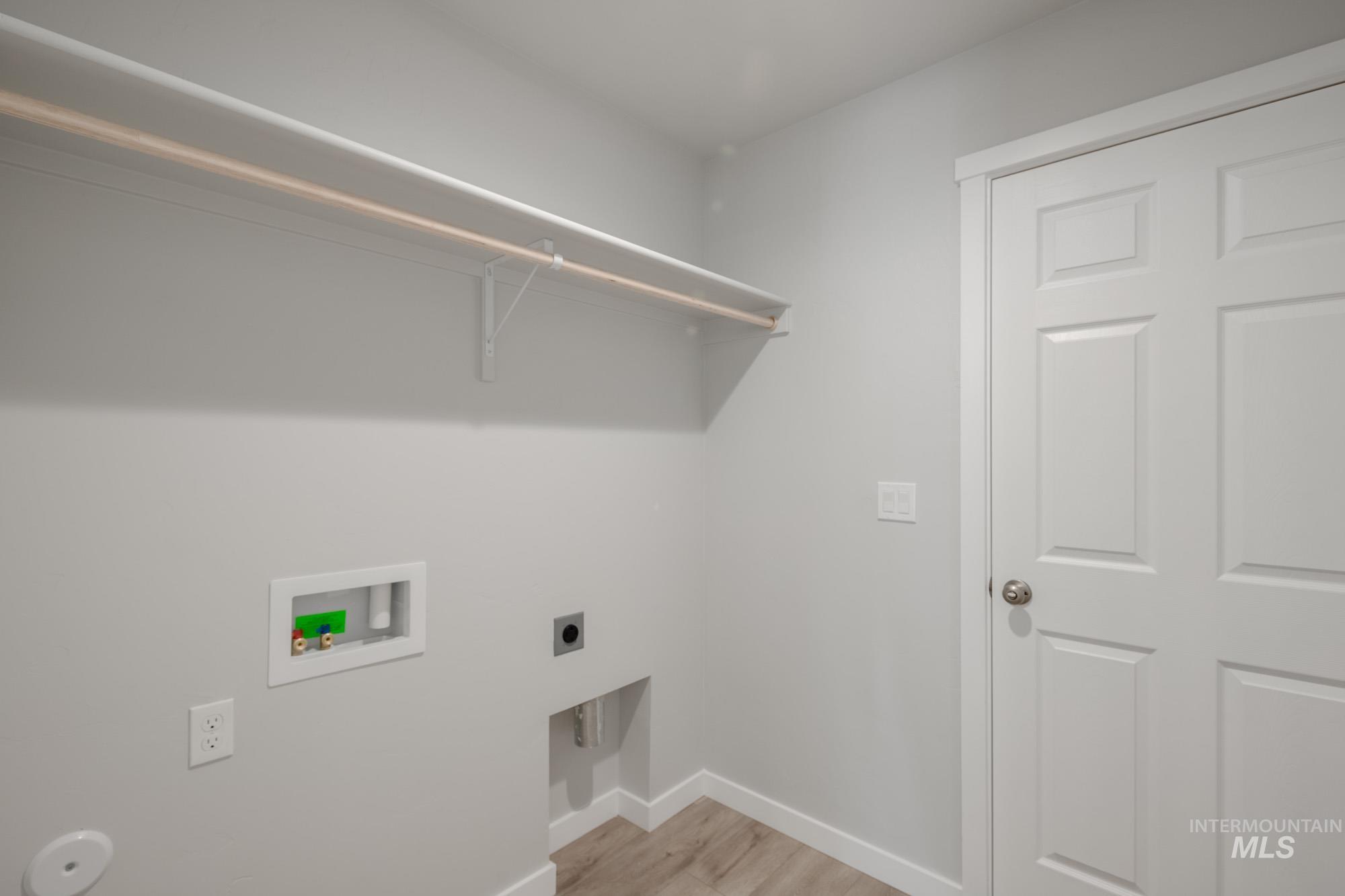 Laundry area featuring electric dryer hookup, light wood-style floors, and washer hookup