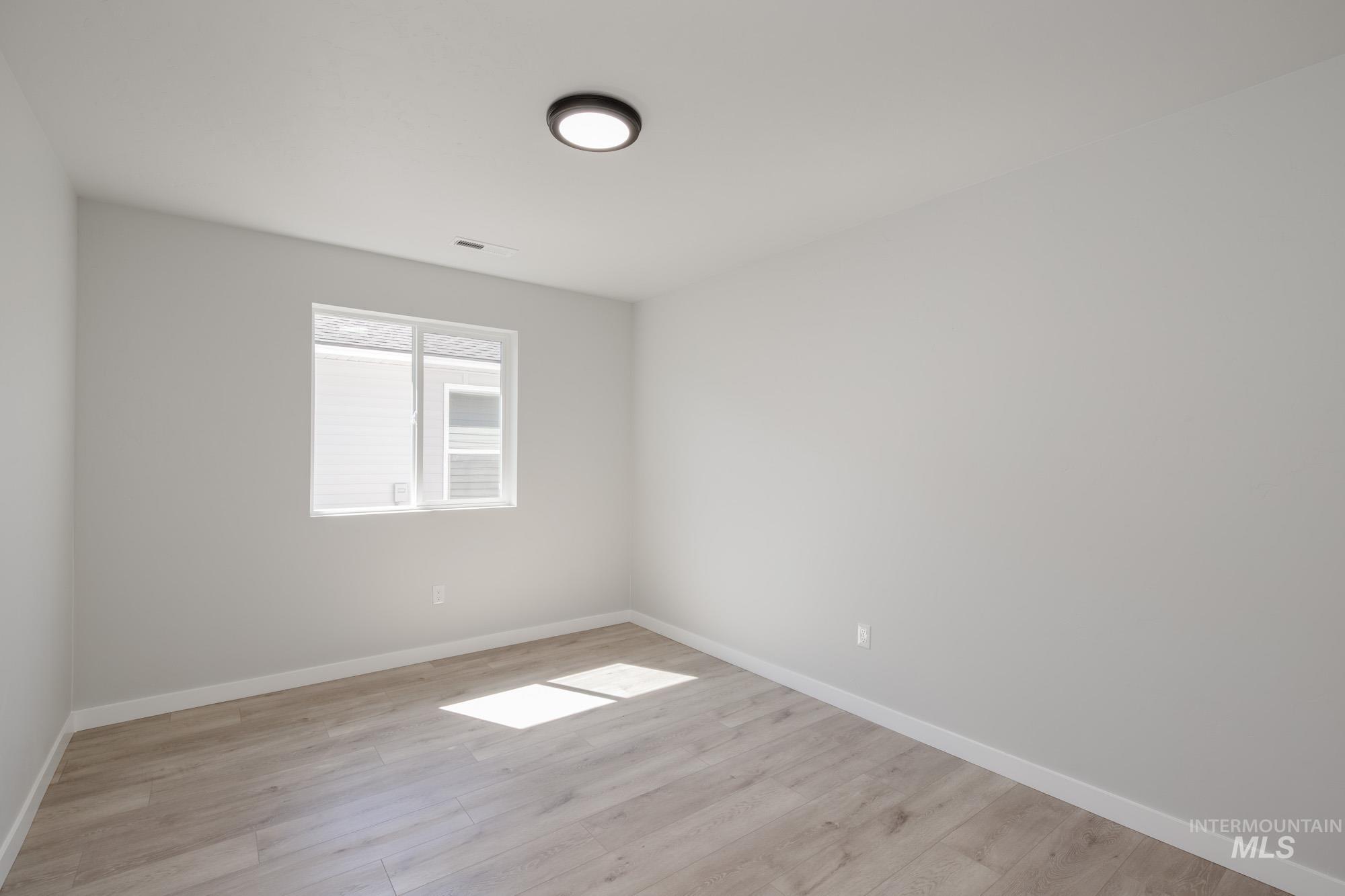 Spare room featuring baseboards and light wood-style floors
