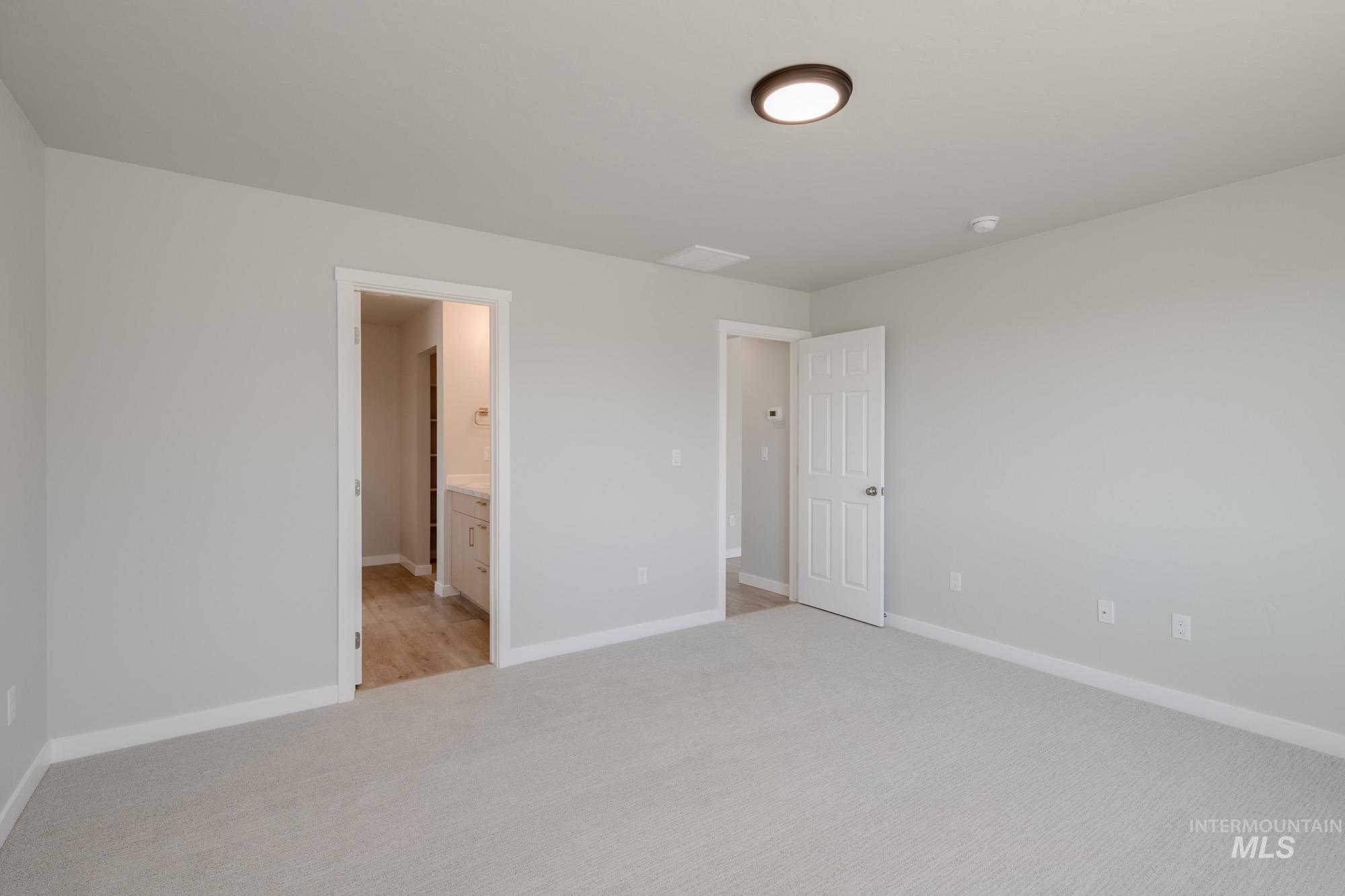 Unfurnished bedroom featuring light colored carpet and connected bathroom