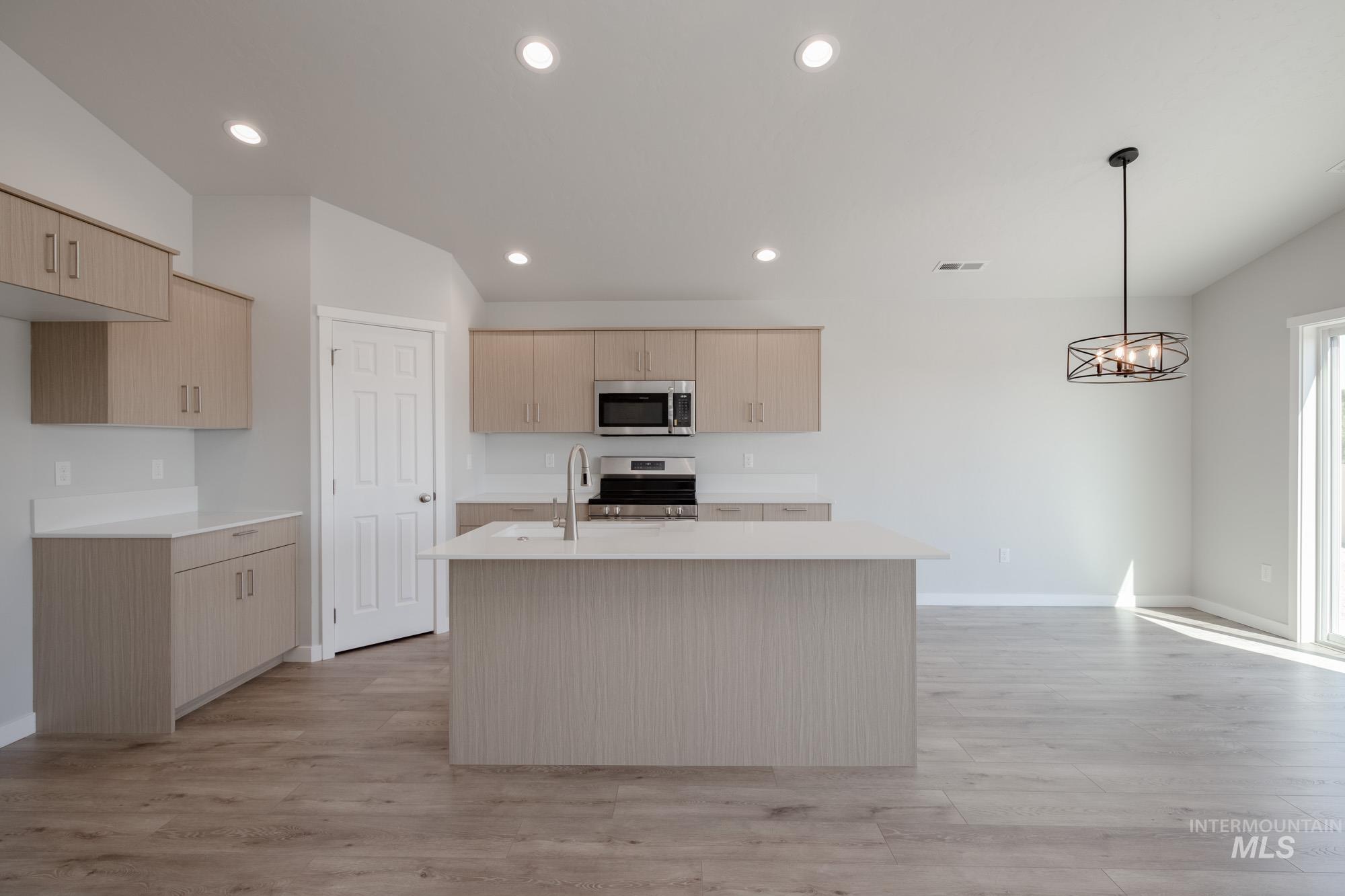 Kitchen featuring light brown cabinets, a center island with sink, appliances with stainless steel finishes, light wood-type flooring, and recessed lighting