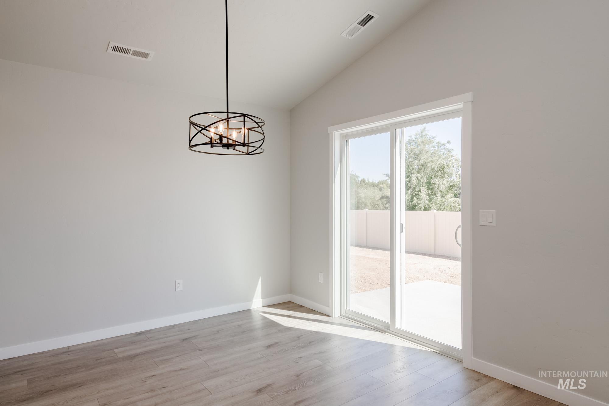 Unfurnished dining area featuring lofted ceiling, light wood-type flooring, and a chandelier