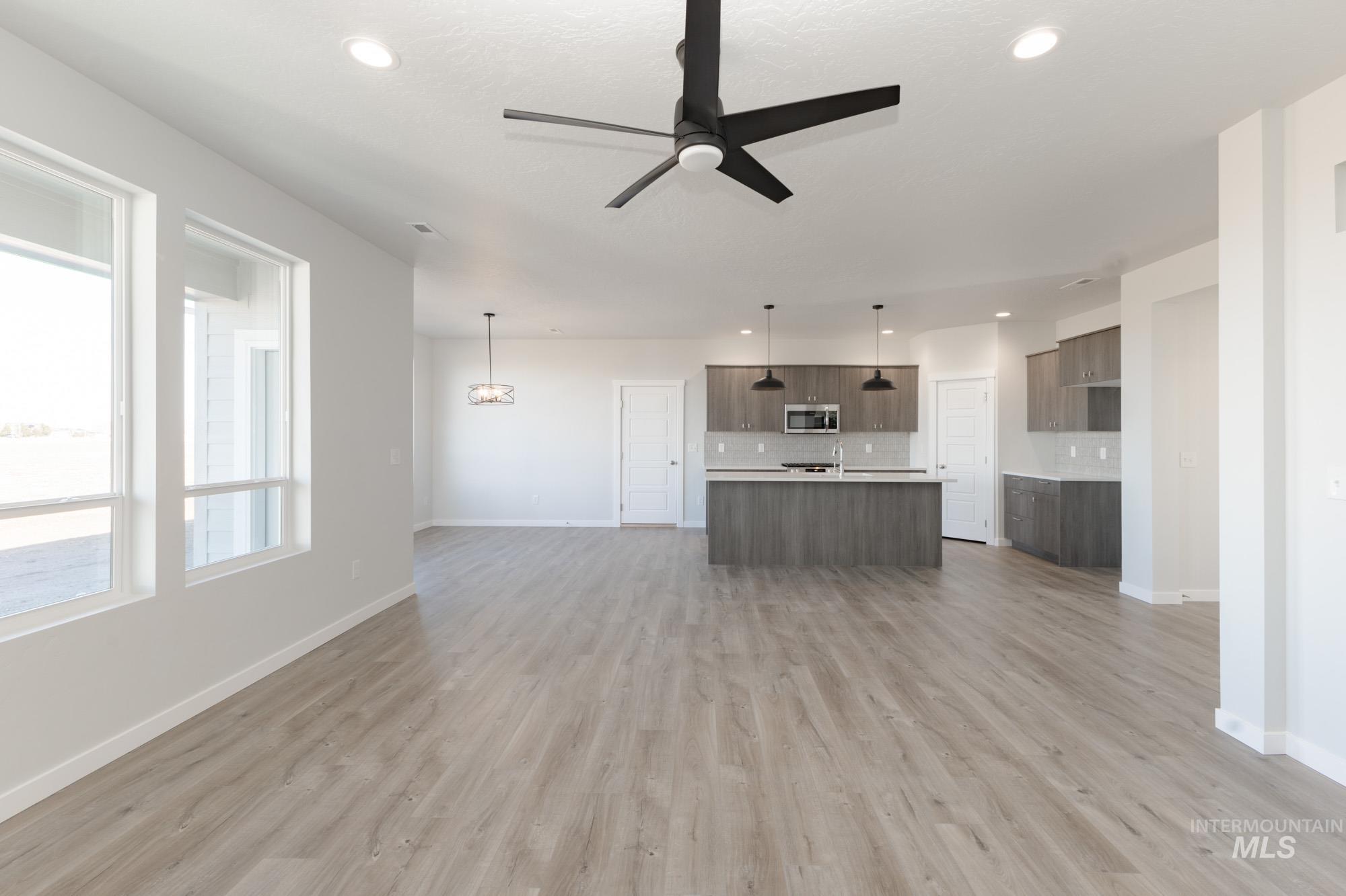 Unfurnished living room featuring a ceiling fan, light wood-type flooring, recessed lighting, and a chandelier