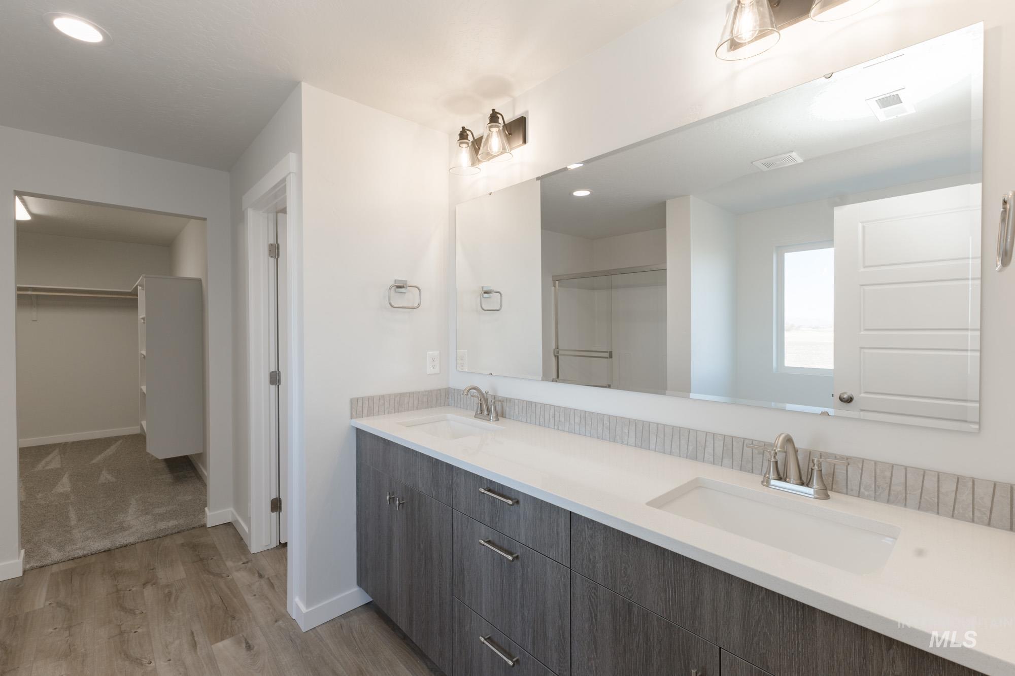 Bathroom with double vanity, recessed lighting, light wood-type flooring, and a walk in closet