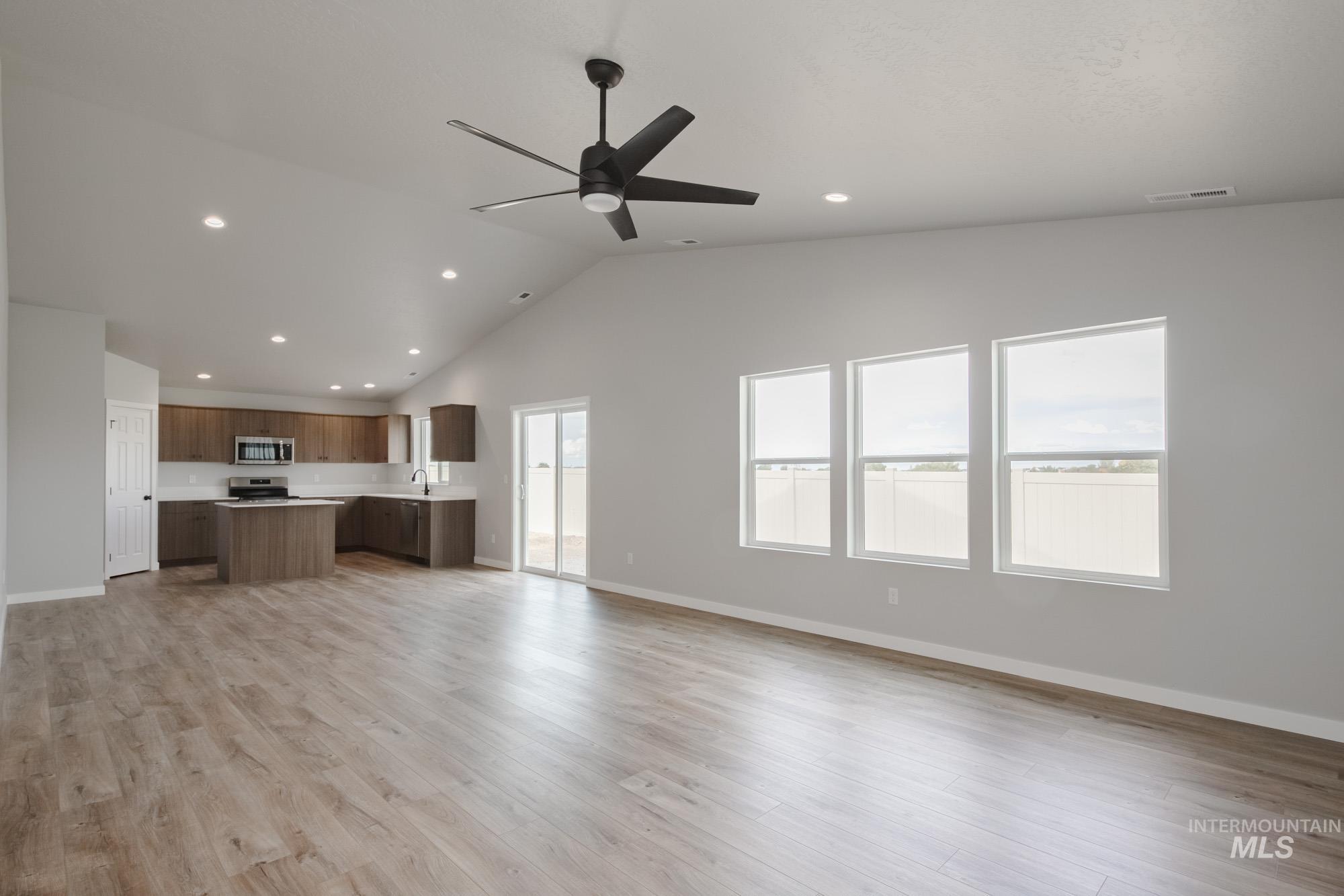 Unfurnished living room featuring light wood-style floors, recessed lighting, high vaulted ceiling, and ceiling fan