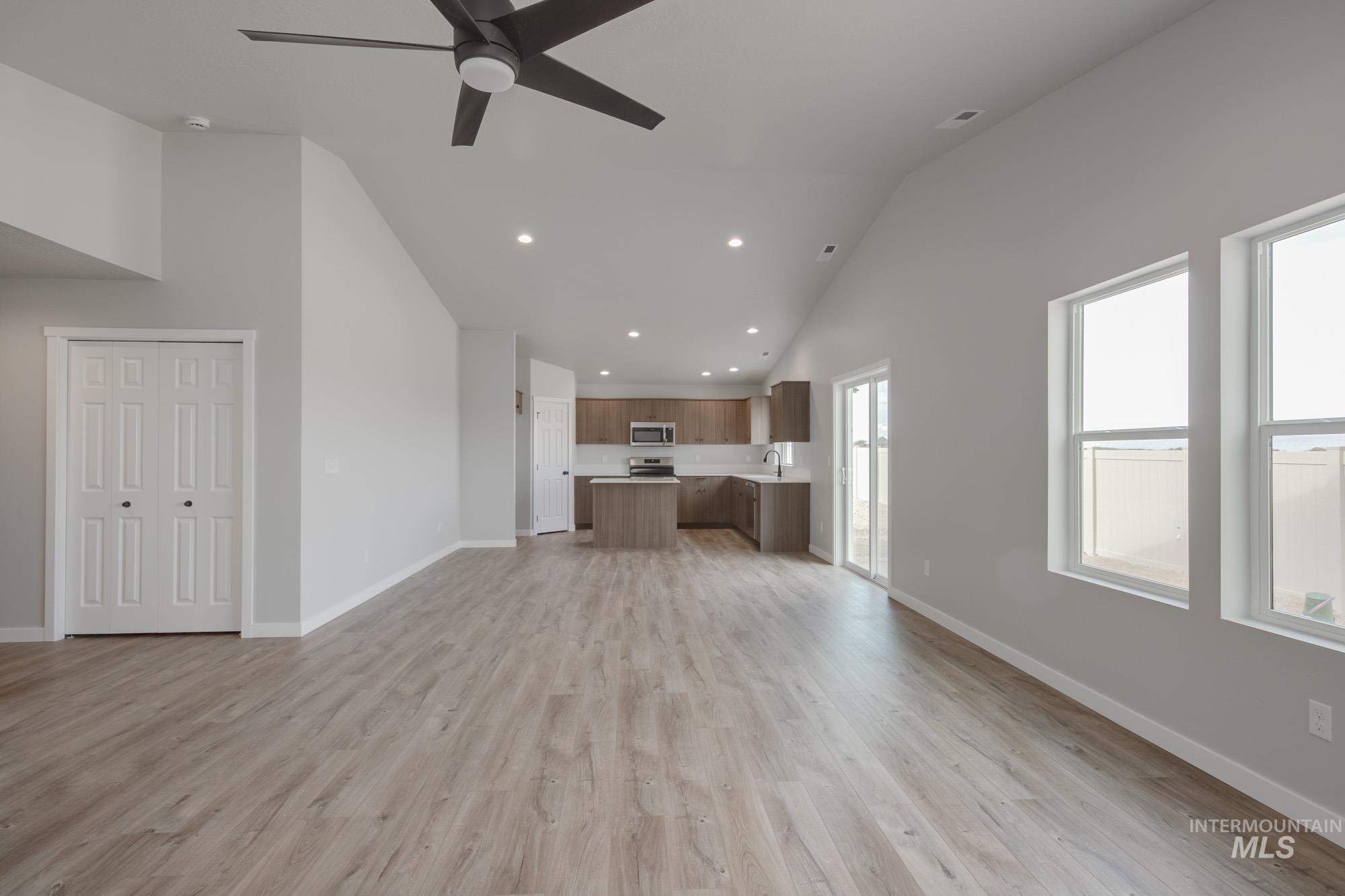 Unfurnished living room with recessed lighting, light wood-type flooring, ceiling fan, and high vaulted ceiling