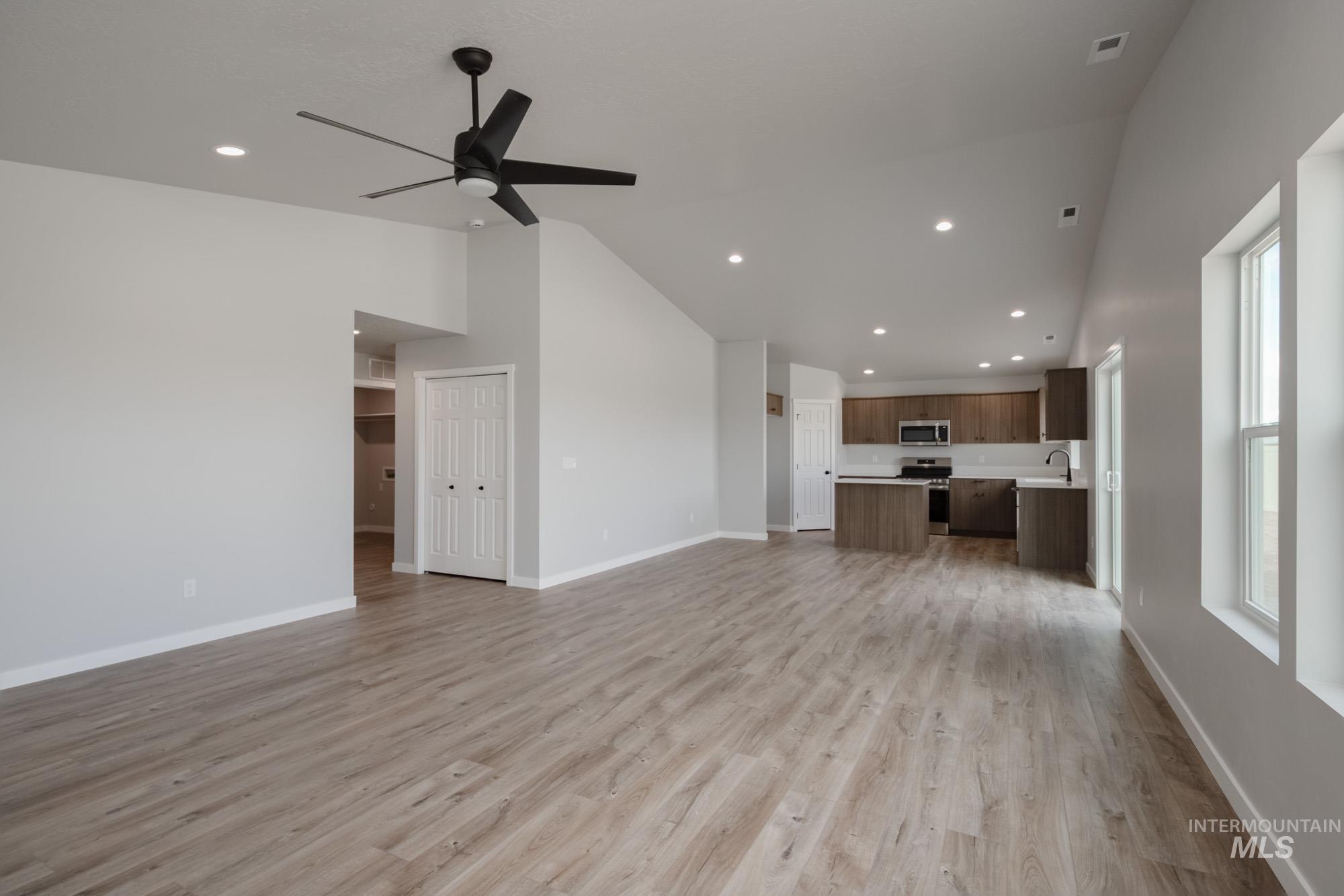Unfurnished living room featuring lofted ceiling, light wood finished floors, recessed lighting, and a ceiling fan