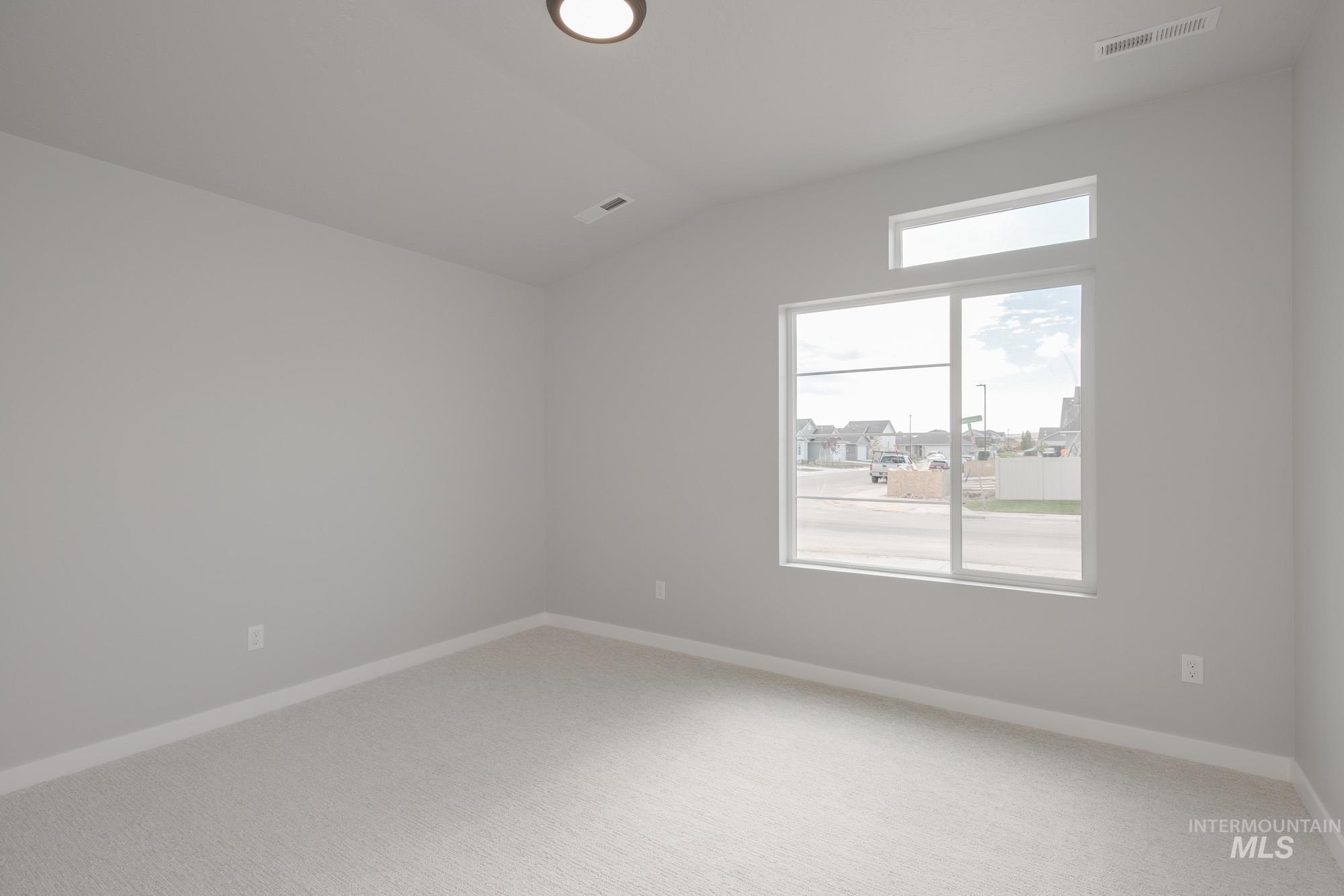 Unfurnished room featuring vaulted ceiling and carpet floors