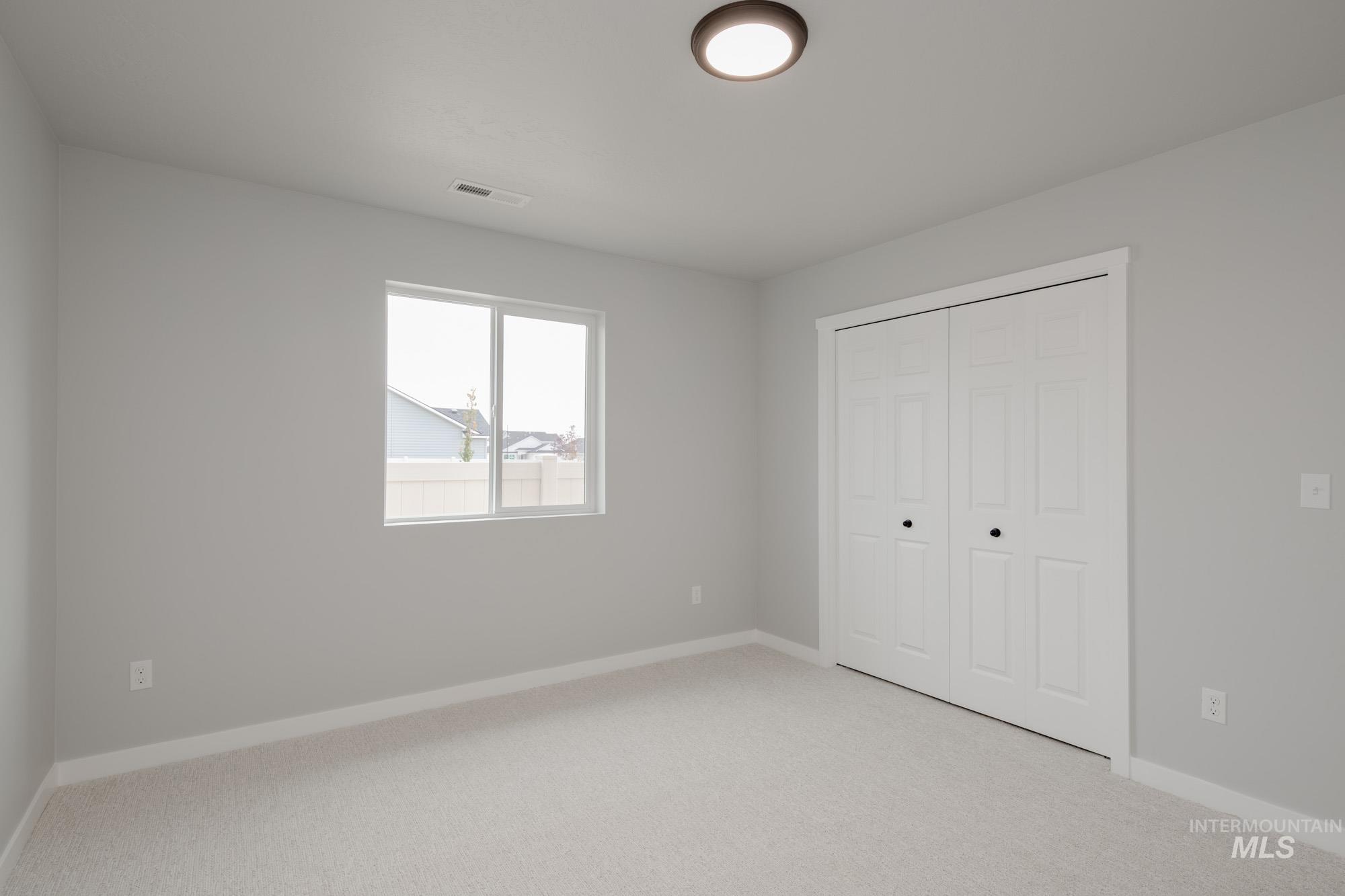 Unfurnished bedroom with light colored carpet and a closet