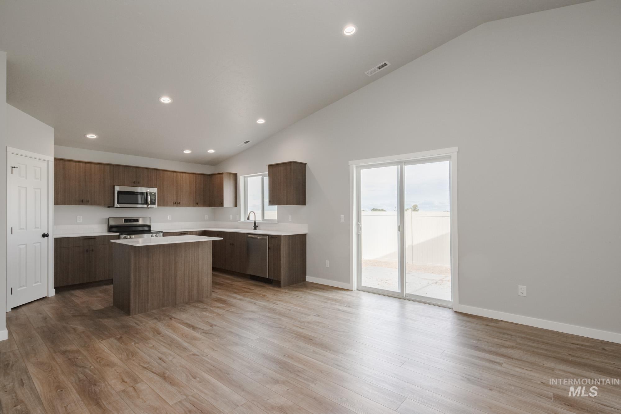 Kitchen with recessed lighting, a kitchen island, plenty of natural light, appliances with stainless steel finishes, and light wood-style flooring