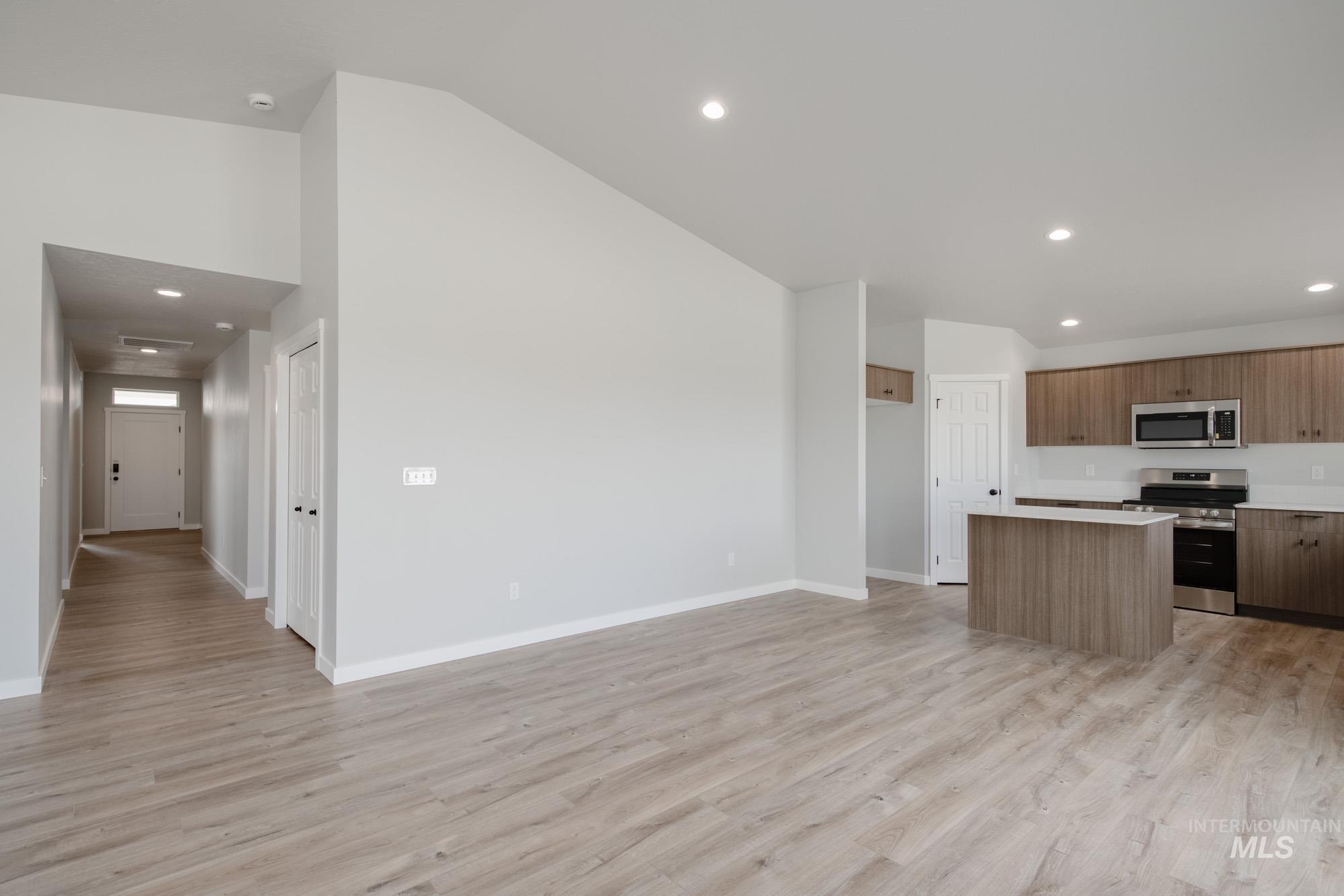 Kitchen with a kitchen island, recessed lighting, light wood-style flooring, light countertops, and stainless steel appliances