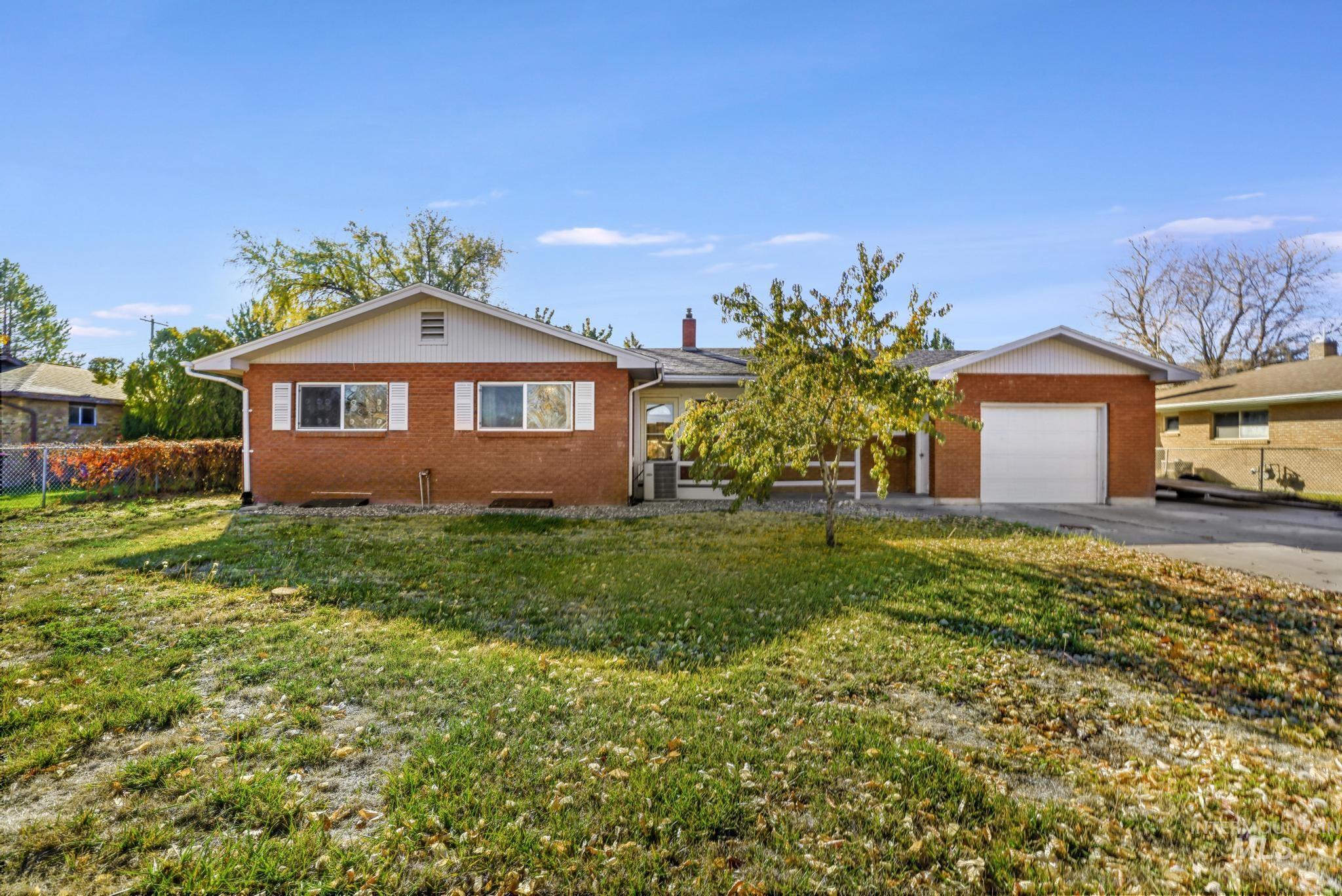 Ranch-style home with brick siding, driveway, an attached garage, and a chimney