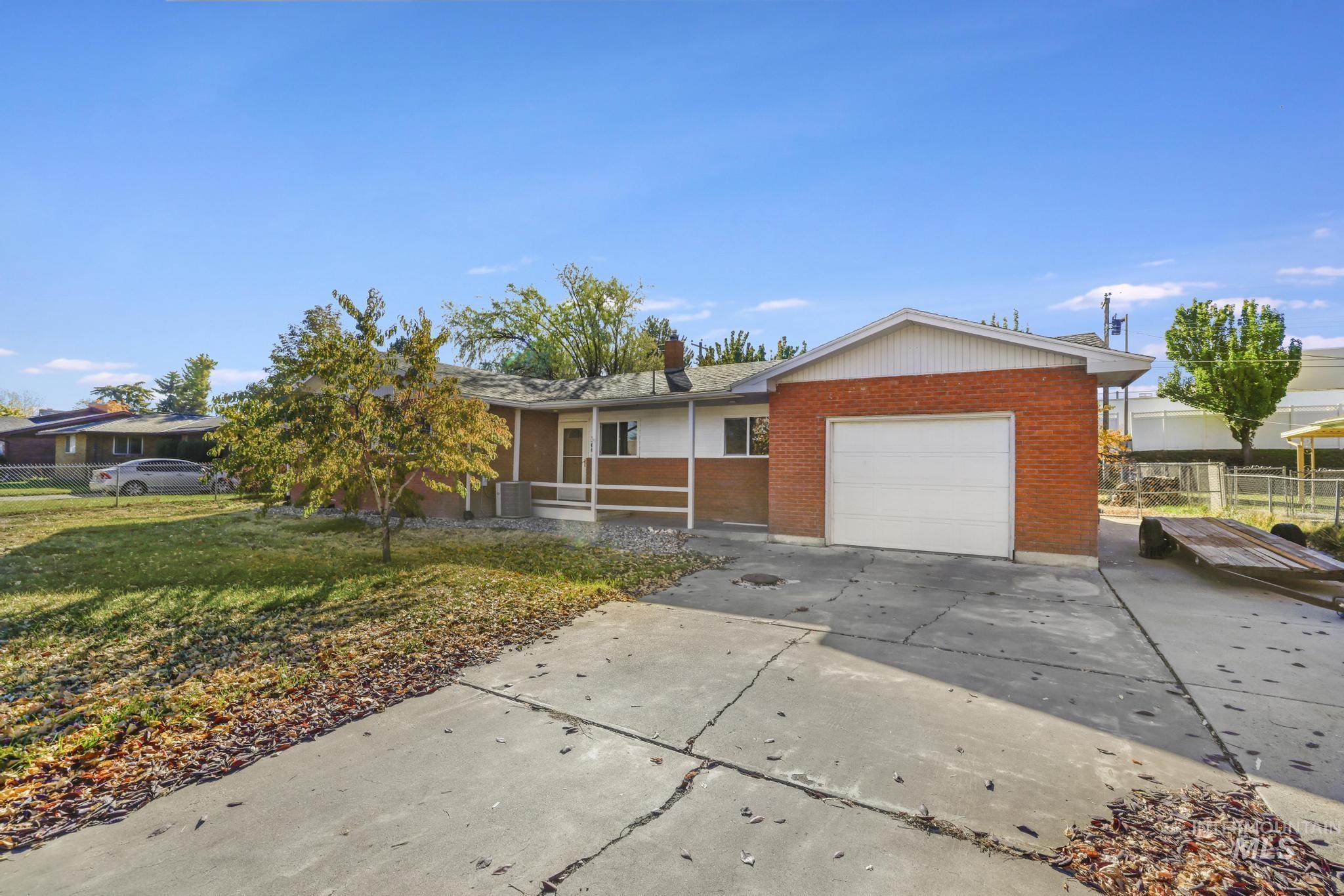 Ranch-style house with brick siding, concrete driveway, a front yard, an attached garage, and a sunroom