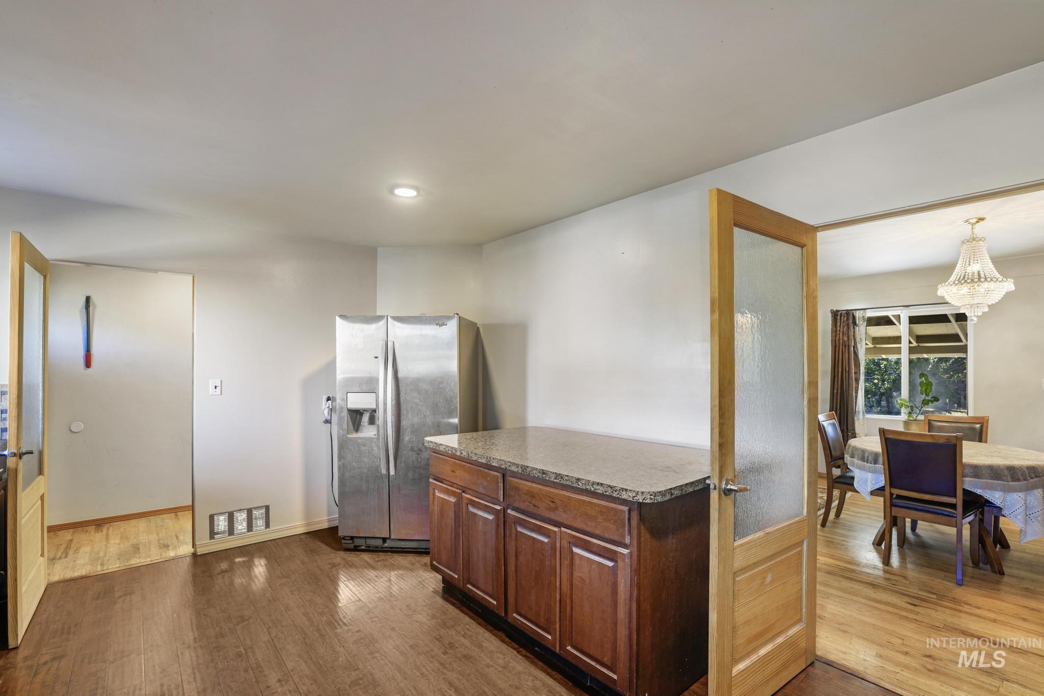 Kitchen with stainless steel refrigerator with ice dispenser, dark wood-type flooring, a chandelier, recessed lighting, and decorative light fixtures