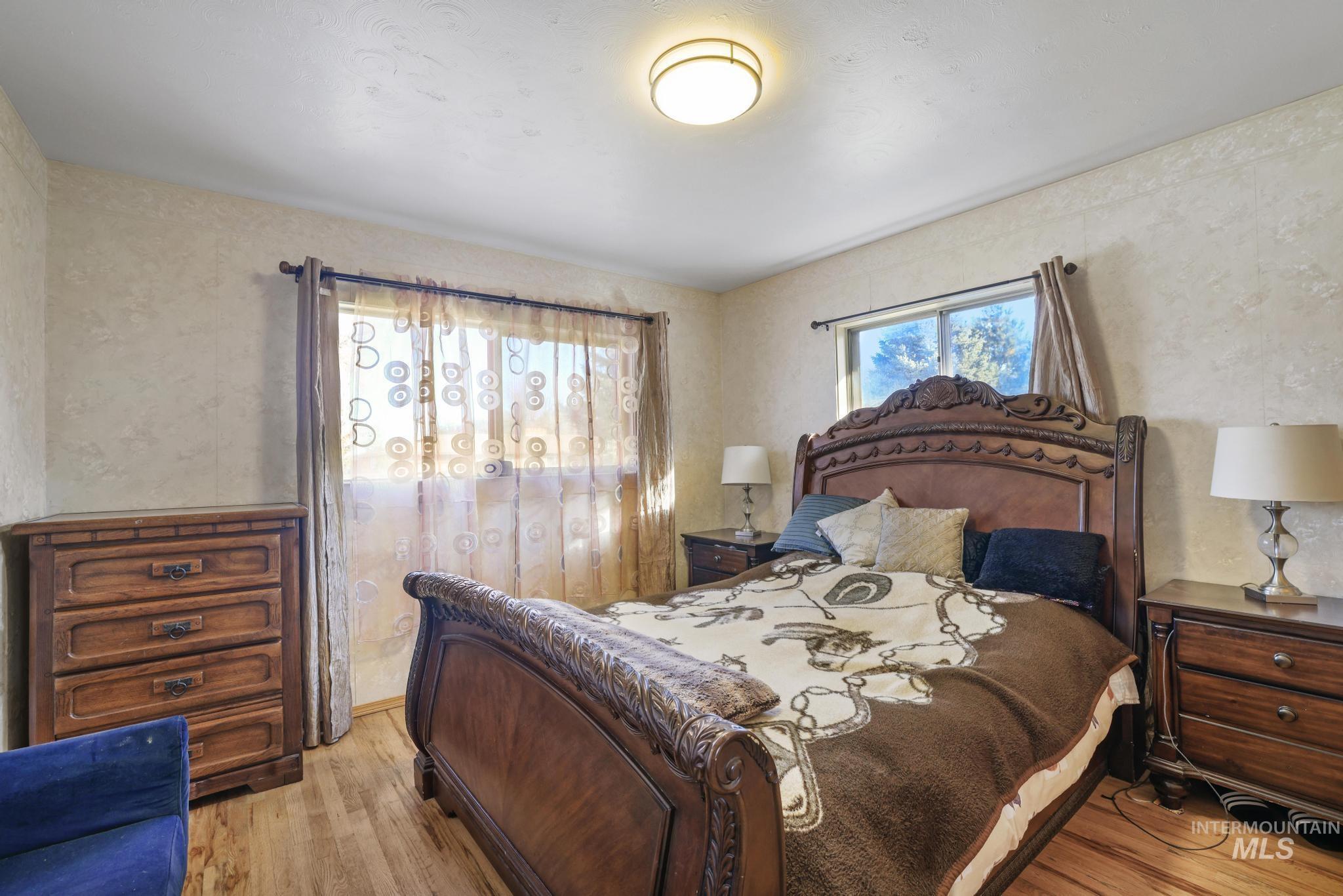 Bedroom with light wood finished floors and wallpapered walls