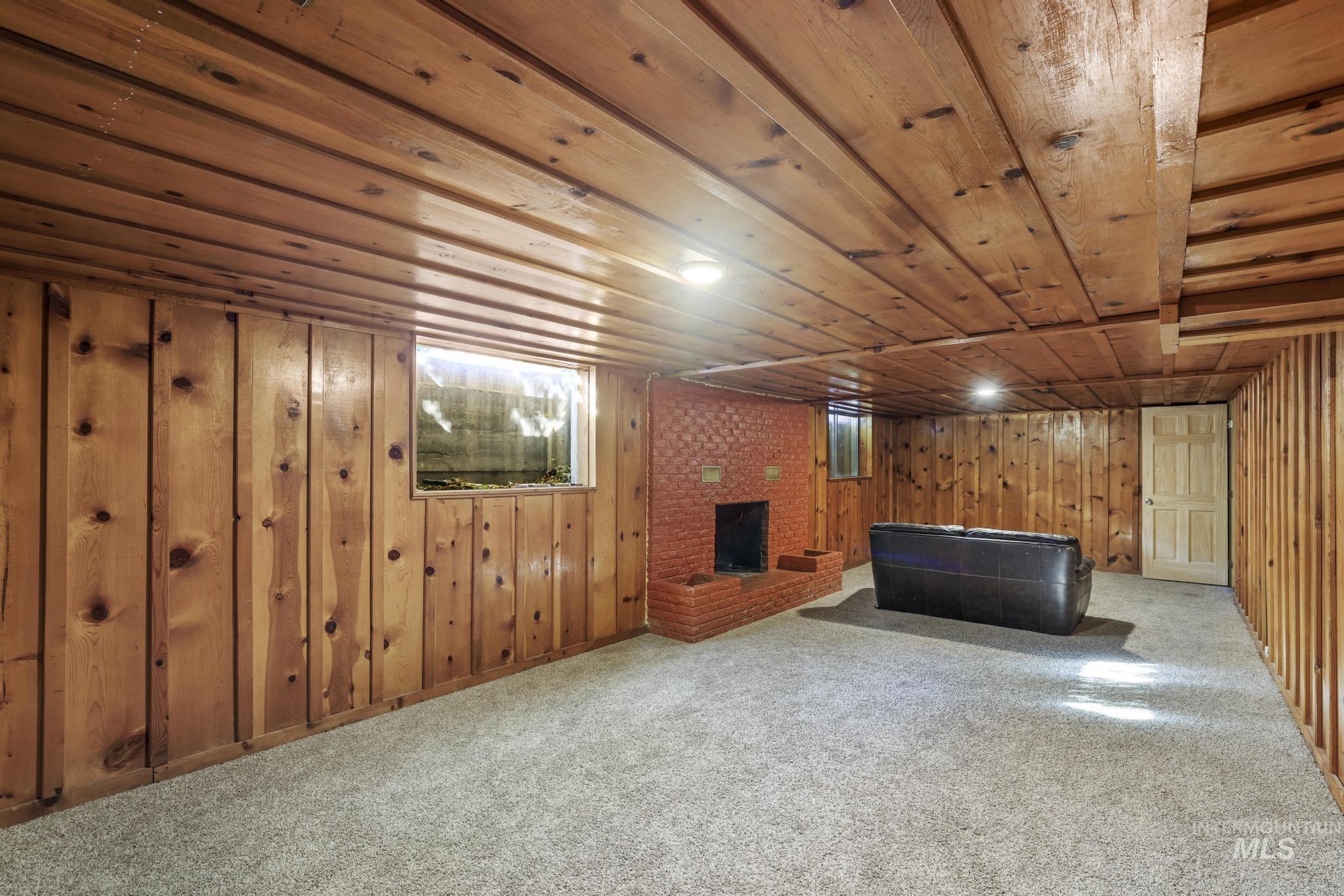 Finished below grade area with carpet, wood walls, a brick fireplace, and wood ceiling