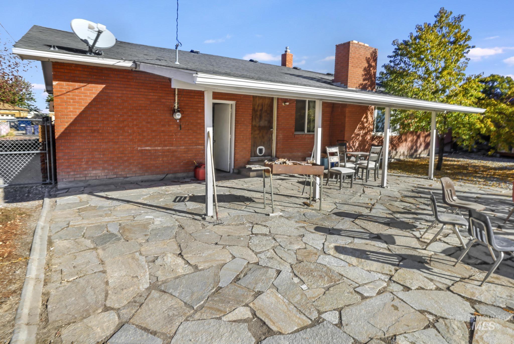 Back of property featuring a patio, a chimney, and brick siding