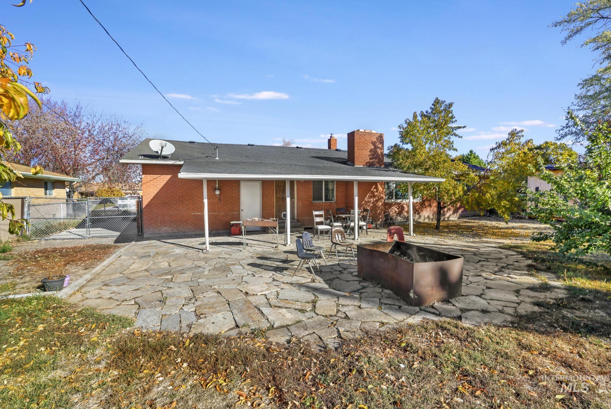 Back of house featuring a patio area, a chimney, a gate, and brick siding