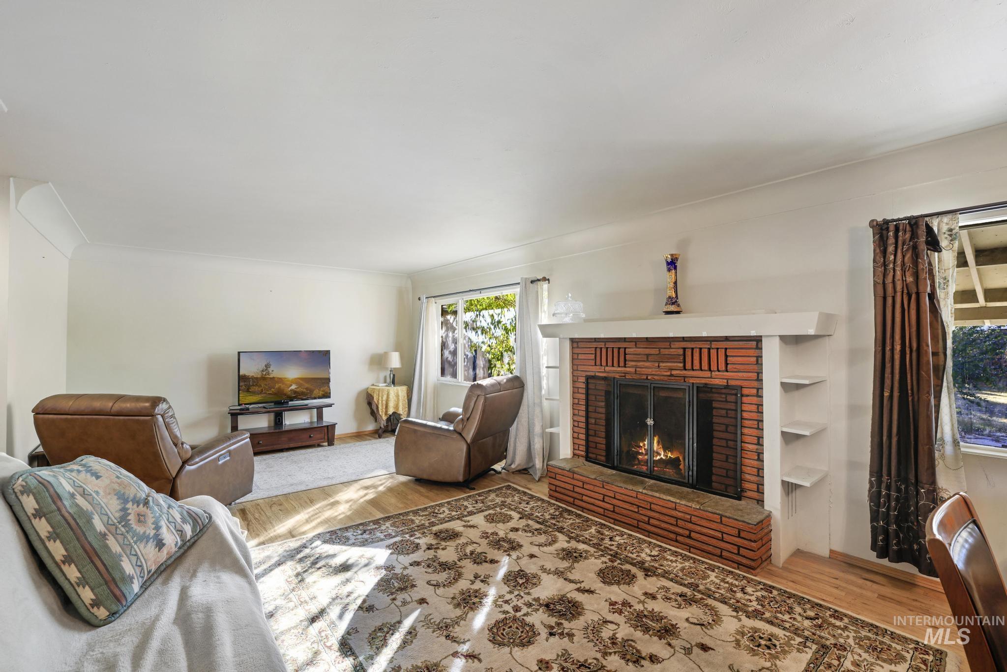 Living room featuring a fireplace, light wood-style floors, and crown molding