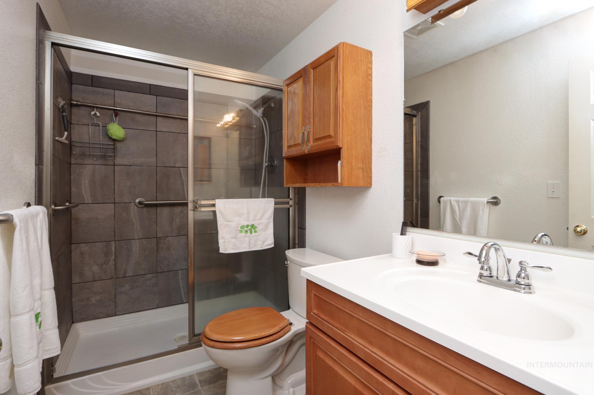 Full bathroom with vanity, a stall shower, a textured ceiling, and light tile patterned floors