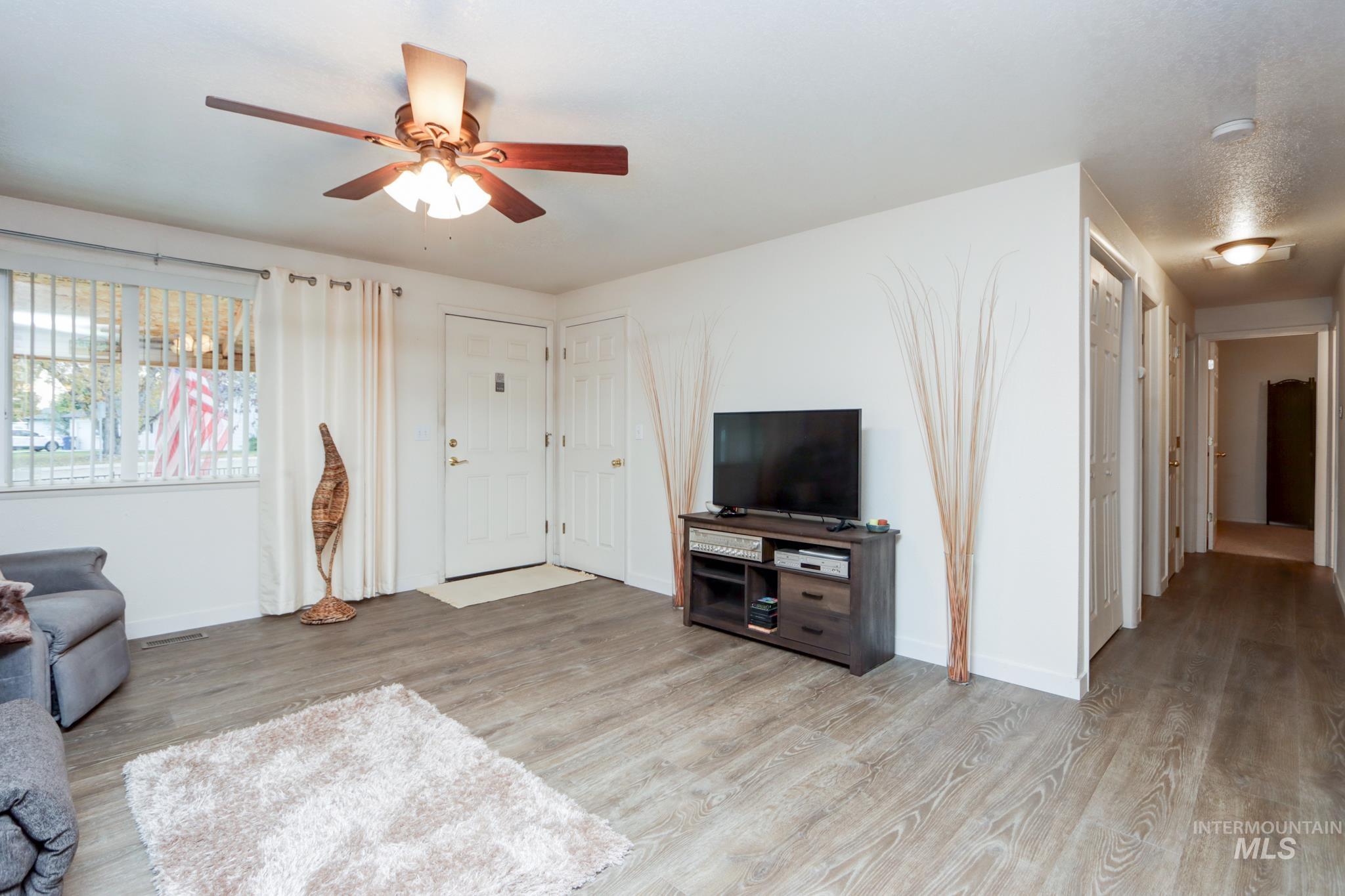 Living area with light wood finished floors and ceiling fan
