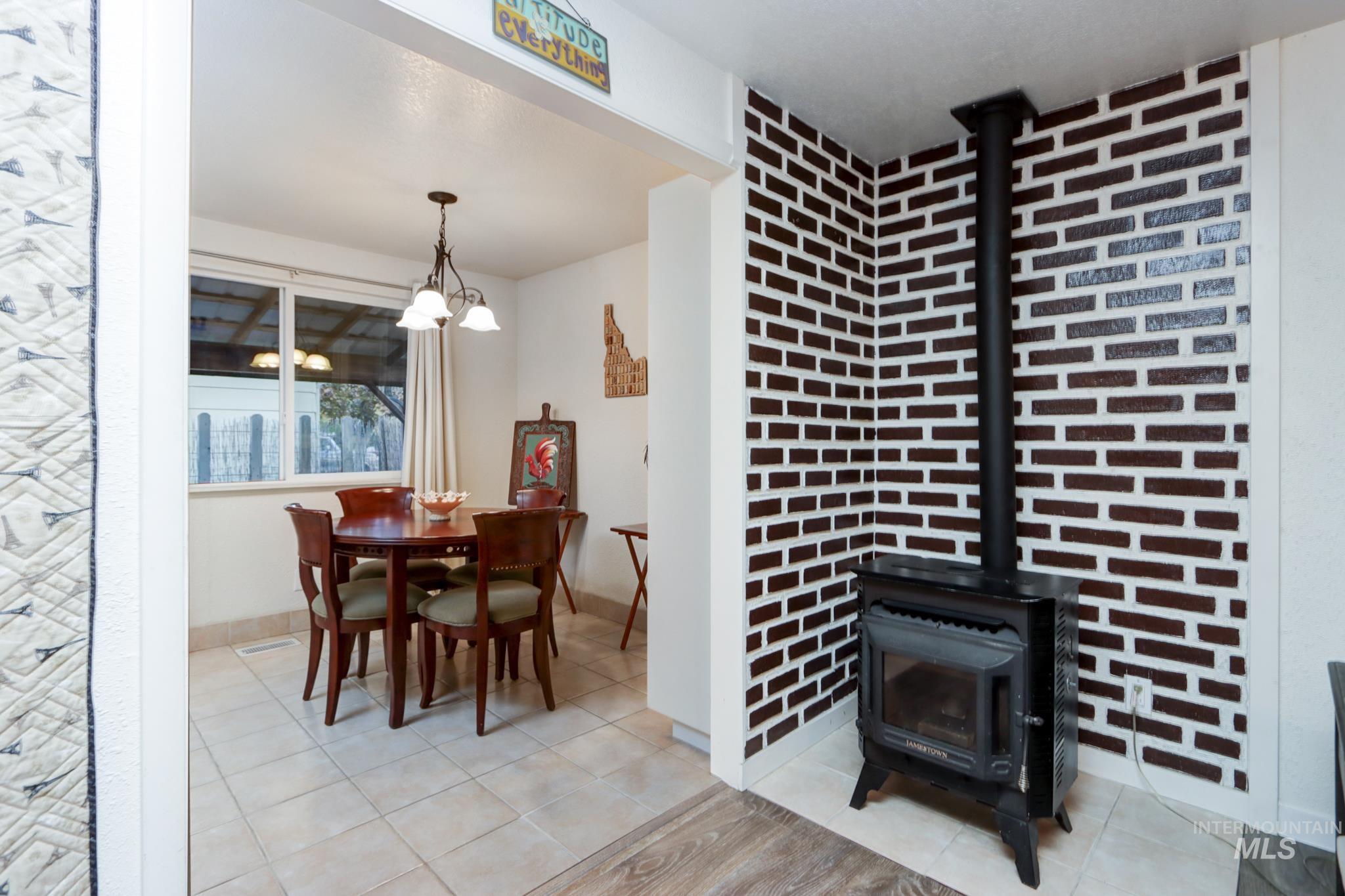 Dining space featuring a wood stove and light tile patterned flooring
