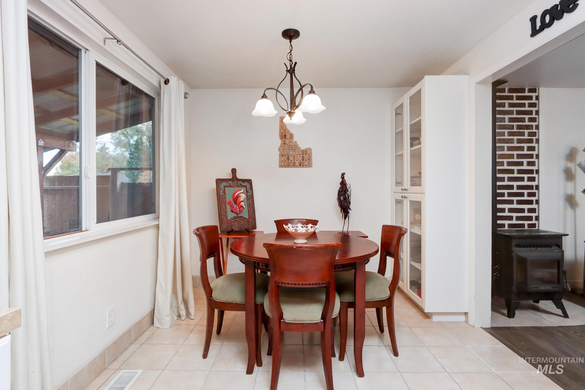 Dining area featuring a wood stove, light tile patterned flooring, and a chandelier