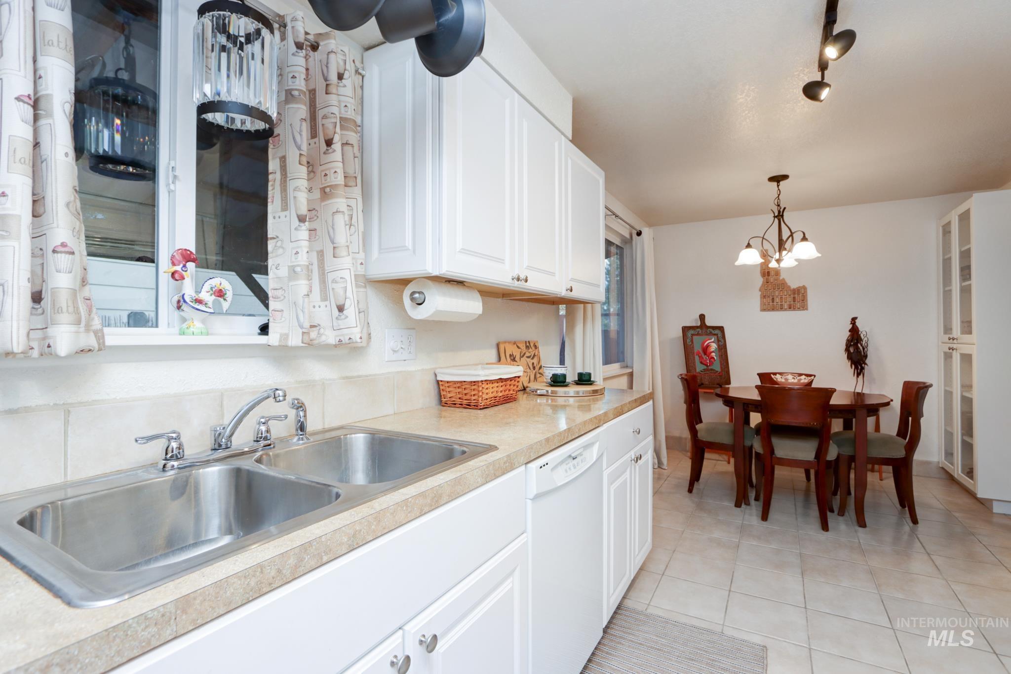 Kitchen with white cabinetry, light countertops, light tile patterned floors, and white dishwasher