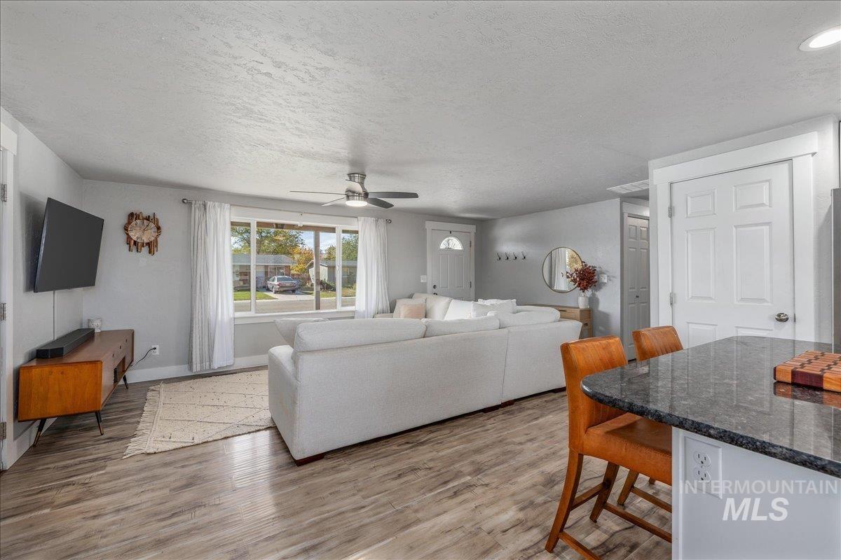 Living area with light wood-type flooring, ceiling fan, and a textured ceiling