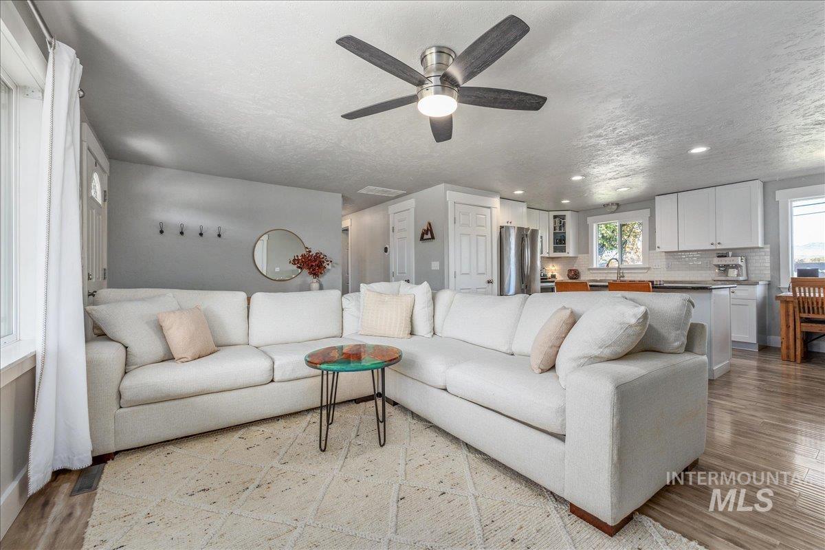 Living room featuring a textured ceiling, light wood-style floors, recessed lighting, and a ceiling fan