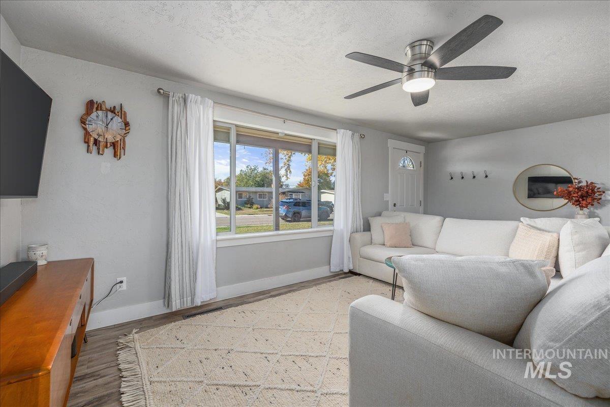 Living room with a textured ceiling, wood finished floors, and ceiling fan