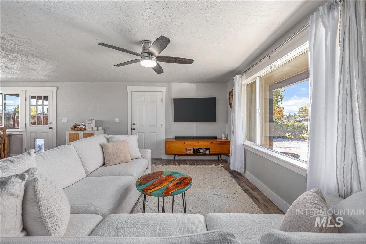 Living area featuring wood finished floors, a textured ceiling, and a ceiling fan