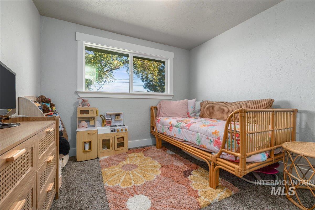 Bedroom with a textured wall, carpet, a textured ceiling, and vaulted ceiling