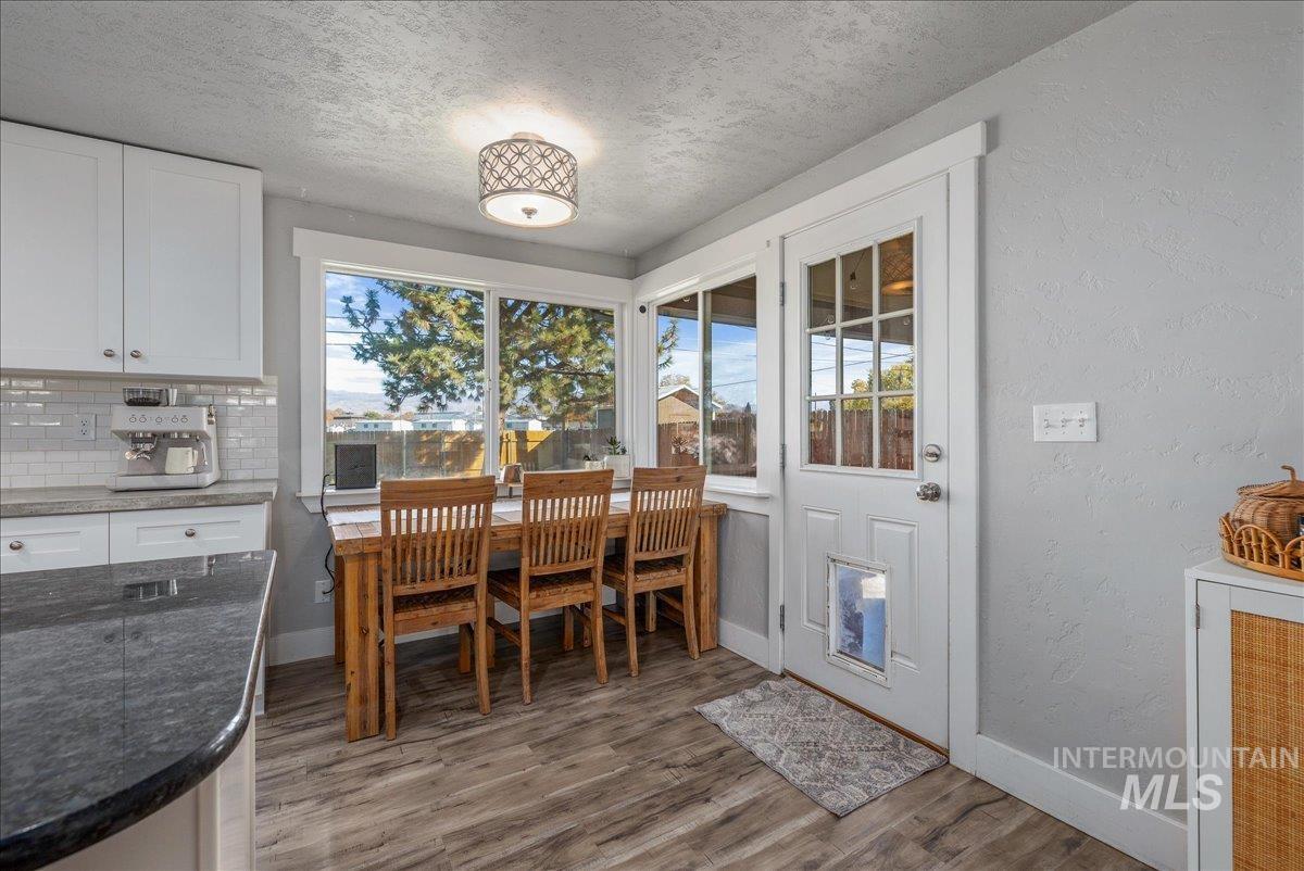 Dining area featuring a textured wall, a textured ceiling, and dark wood finished floors
